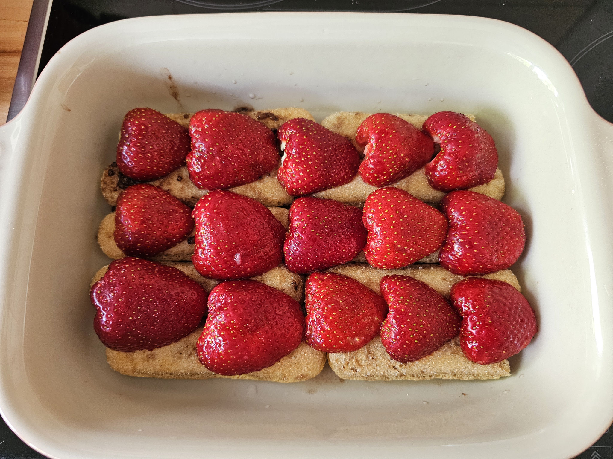 Frische Erdbeeren auf Löffelbiskuit in einer Auflaufform
