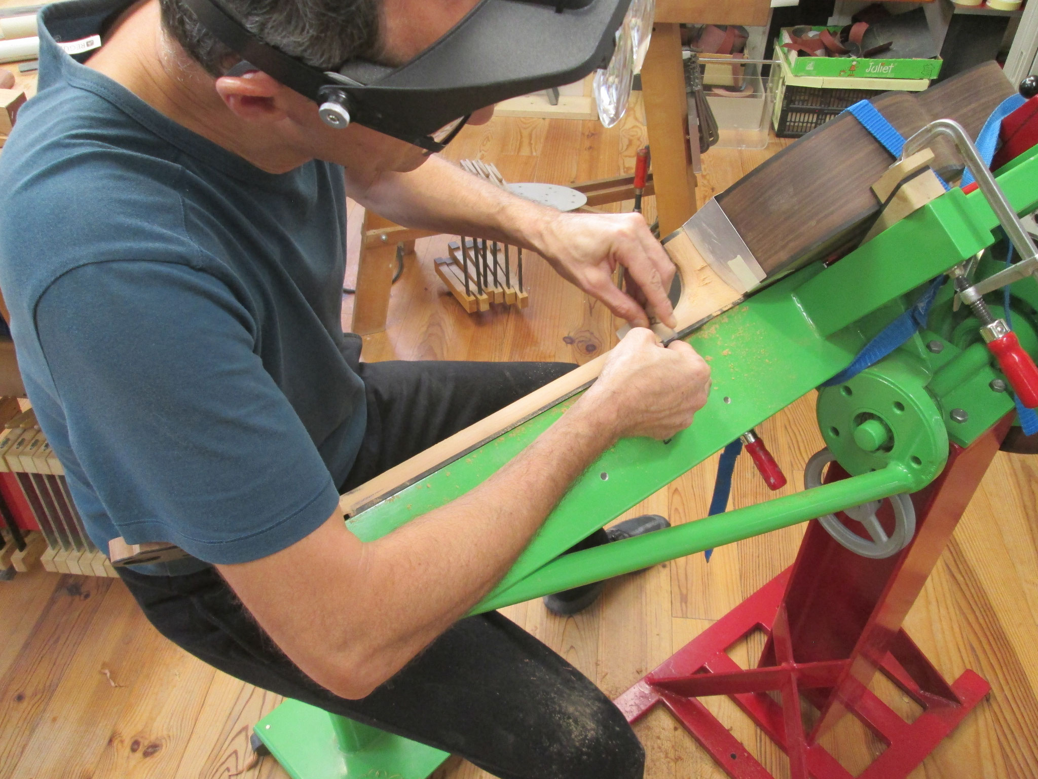 Vue du luthier Hervé Lahoun sculptant le manche de la guitare "La Lenvers"