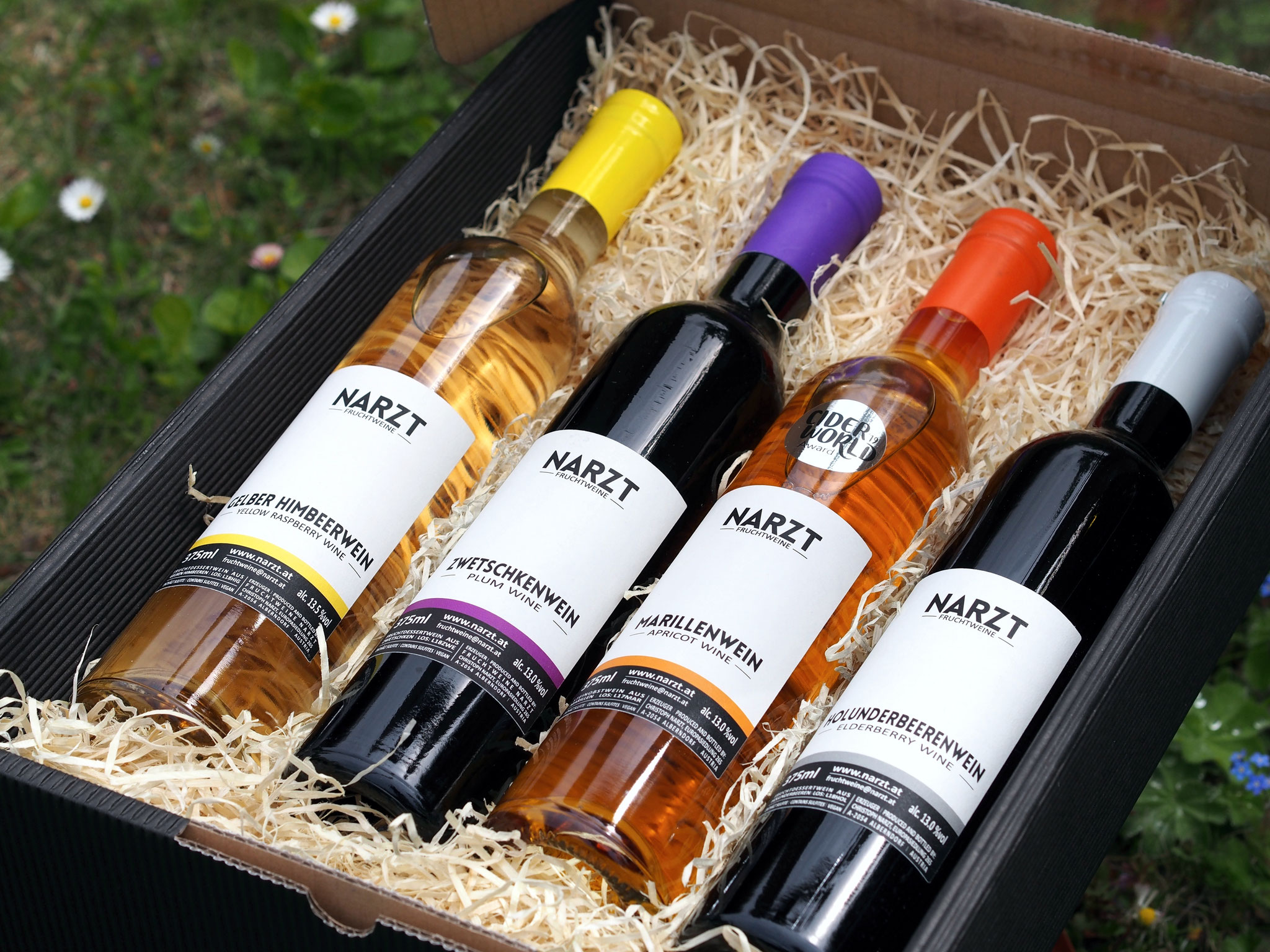 Geschenkbox von NARZT FRUCHTWEINE mit vier 375ml Flaschen der Sorten: Gelbe Himbeere, Zwetschke, Marille und Holunderbeere.