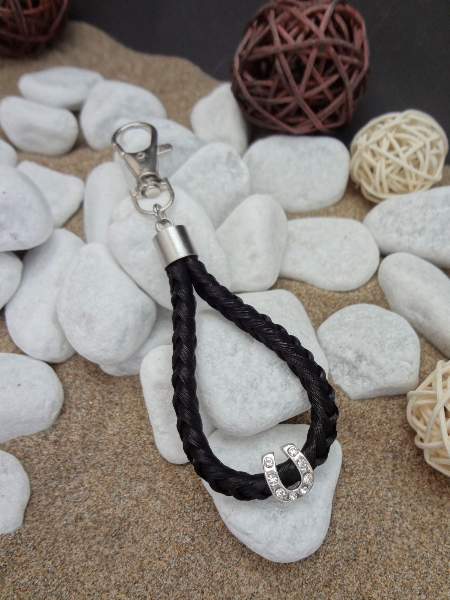 Schlüsselanhänger "Tropfen": Aus schwarzen Strängen geflochten, mit versilberter Perle "Hufeisen" mit Strasssteinen und Endkappe aus Edelstahl - Preis: 35 Euro