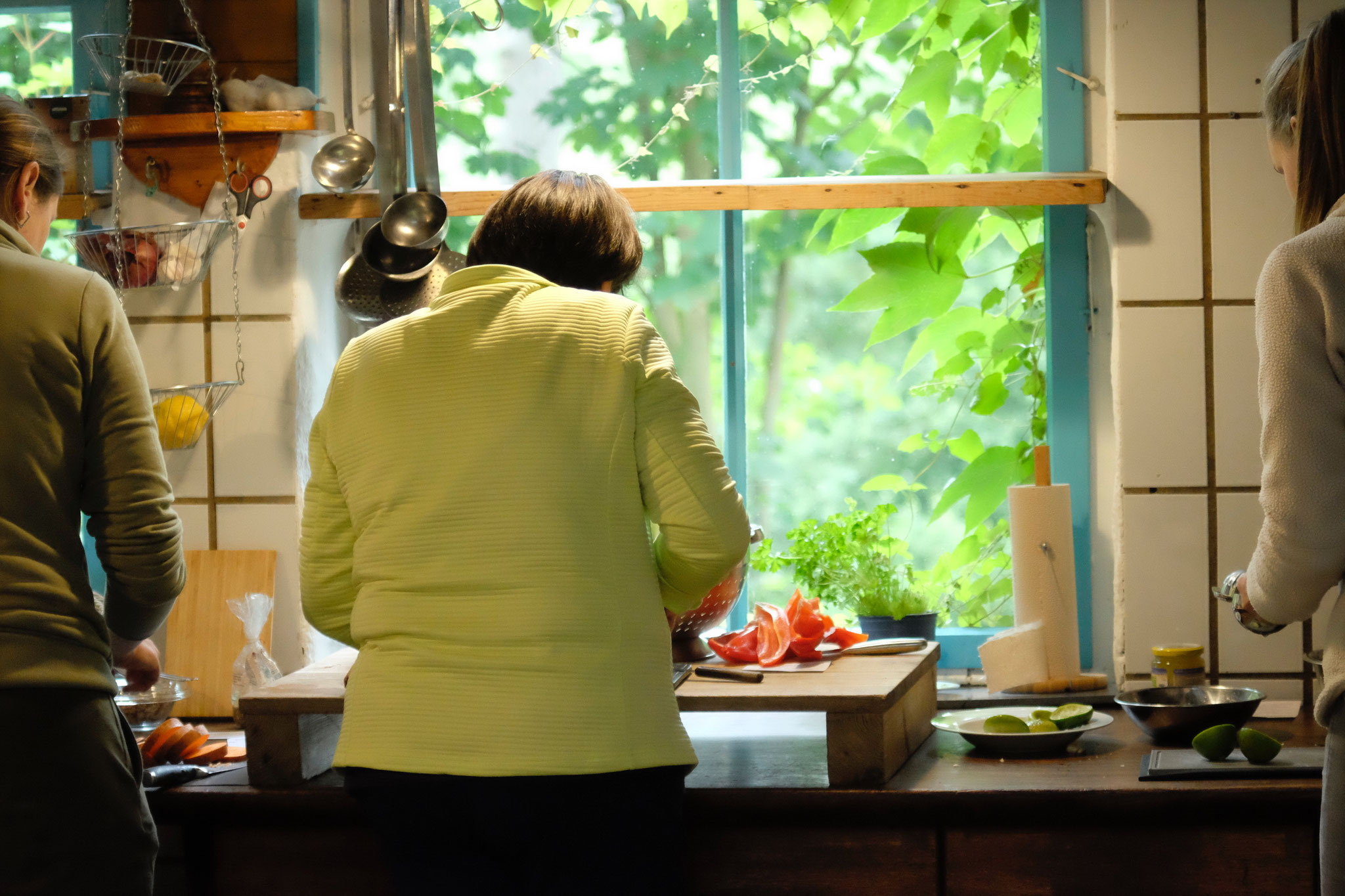 Teilnehmende beim achtsamen Kochen und Schneiden von frischem Gemüse in der Küche und mit Ausblick ins Grüne, beim Seminar zur bewussten Ernährung und Achtsamkeit in der Grube Louise im Westerwald