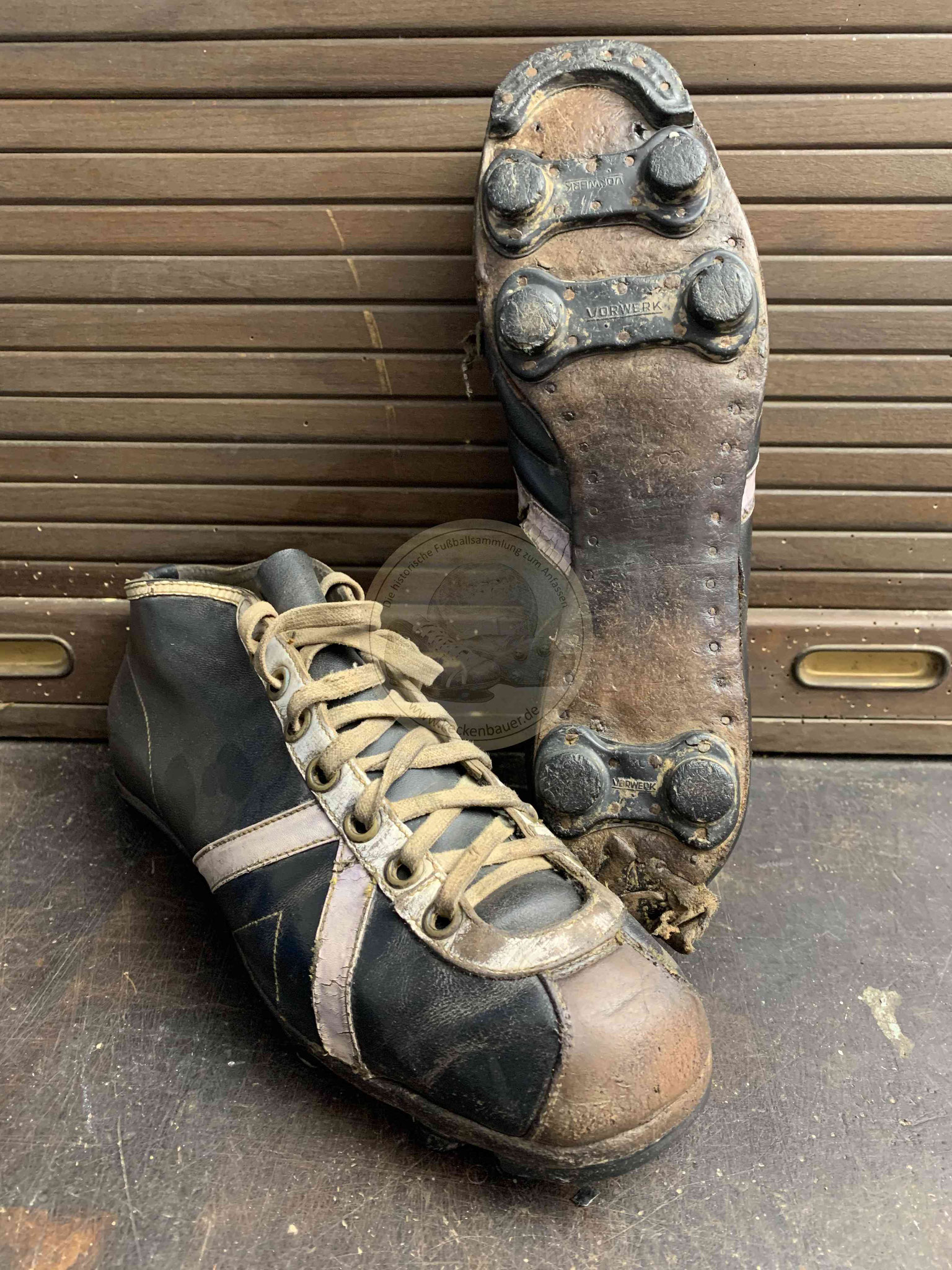 Alte hohe Hummel Fußballschuhe mit Vorwerk-Zwillingsstollen und -Stoppern vorne in schwarzem Leder mit weißen Applikationen und brauner Kappe