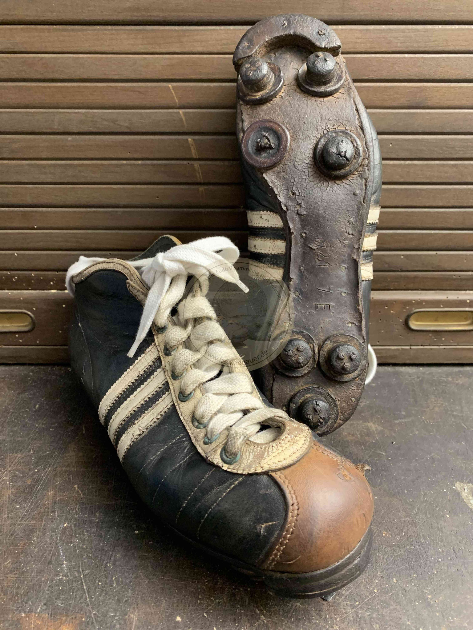 Alte hohe Adidas Fußballschuhe mit Rundstollen und Stoppern vorne in schwarzem Leder mit brauner Kappe