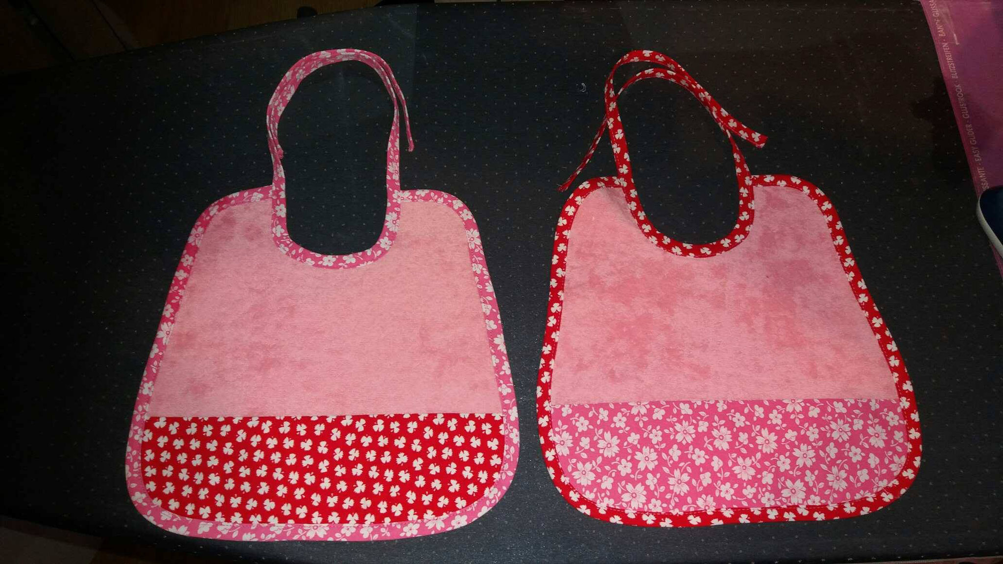 2 coloris de bavoirs  en micro éponge rose : rouge et biais rose/  bavoirs rose  et biais rouge  motifs liberty pour les deux.