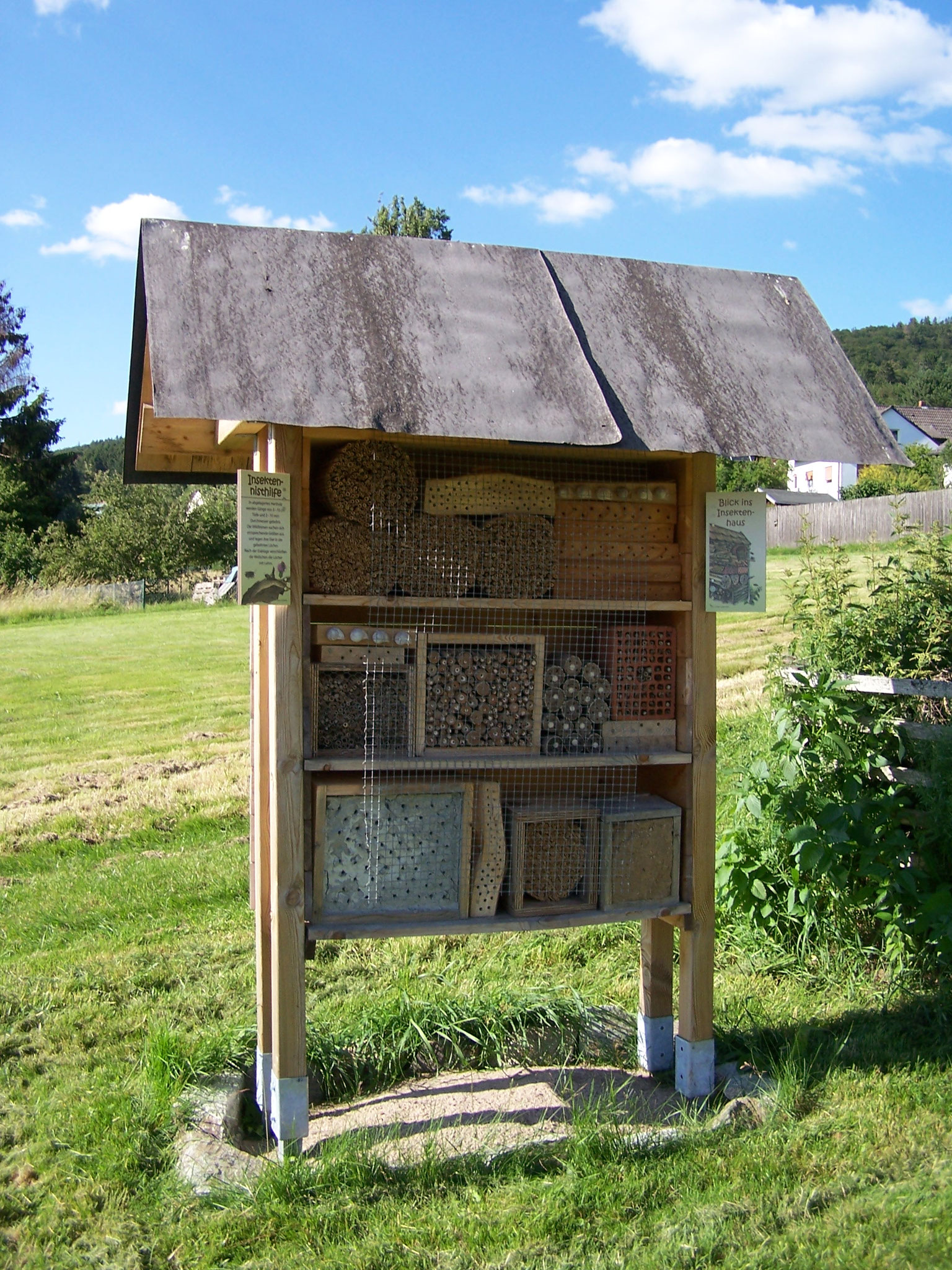 das Insektenhotel mit kleinen Informationstafeln und Flyerboxen auf der Rückseite