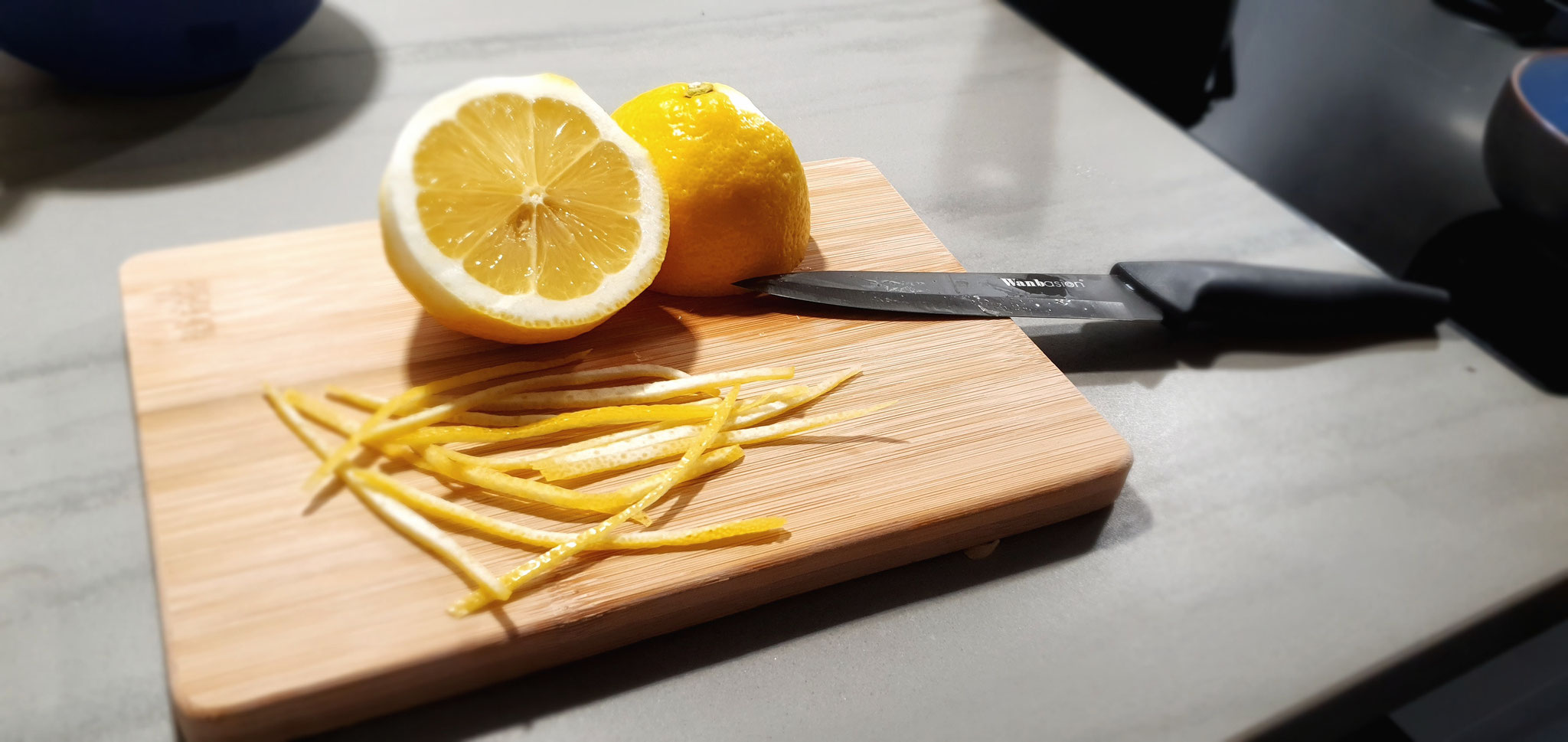 Zitrone halbieren, etwas Schale als Dekor zur Seite legen