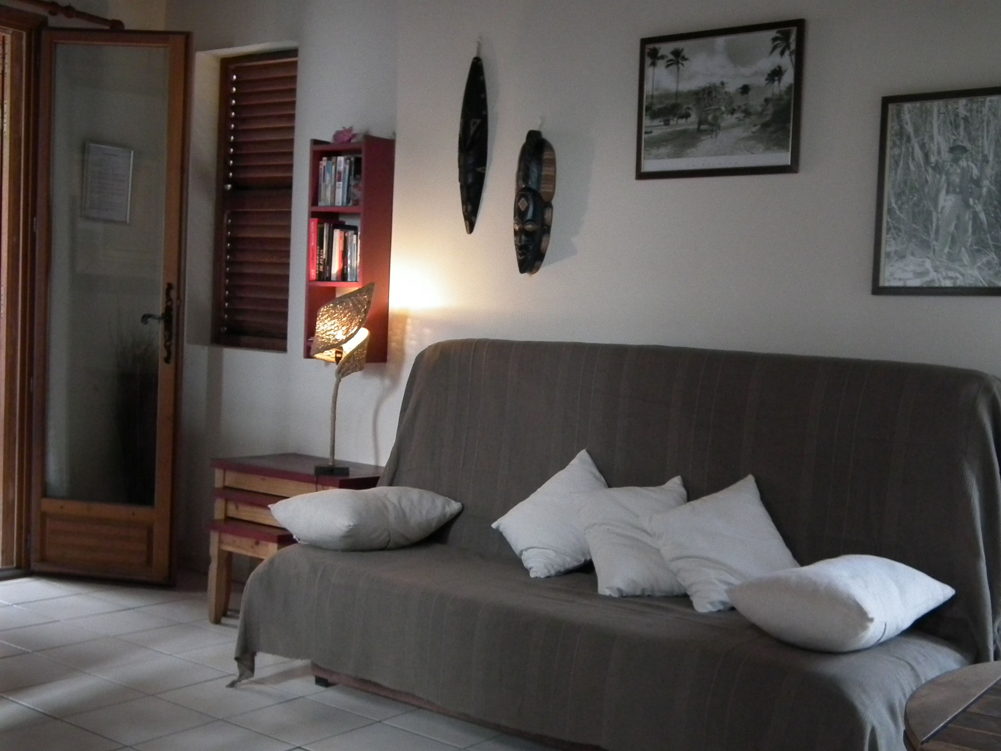 Séjour bungalow n°10 – grand canapé, coussins blancs, boiserie, ambiance tamisée