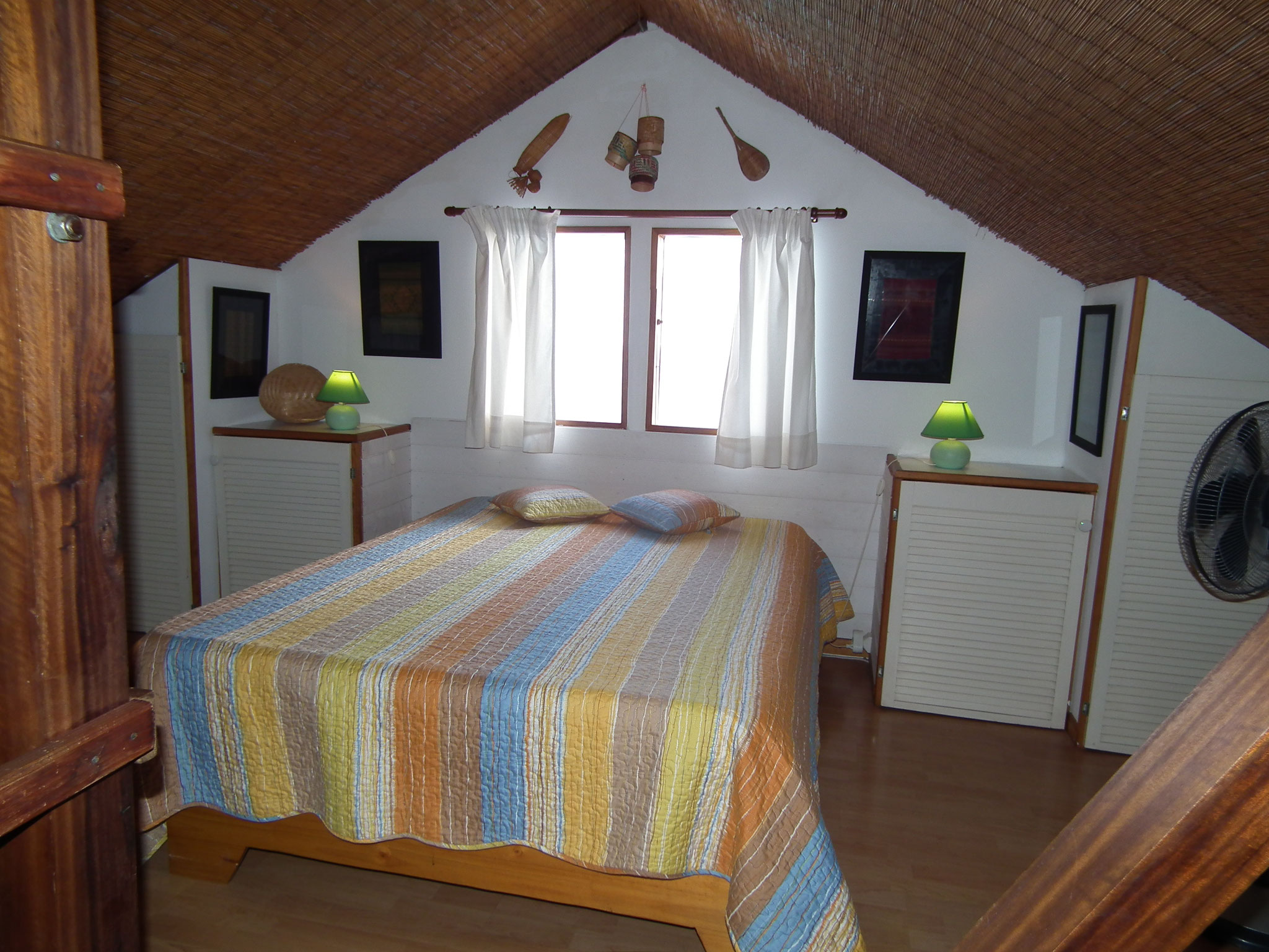 Double bedroom under the eaves with colourful striped bedding, Bungalow 8, bungalow rental Reunion Island