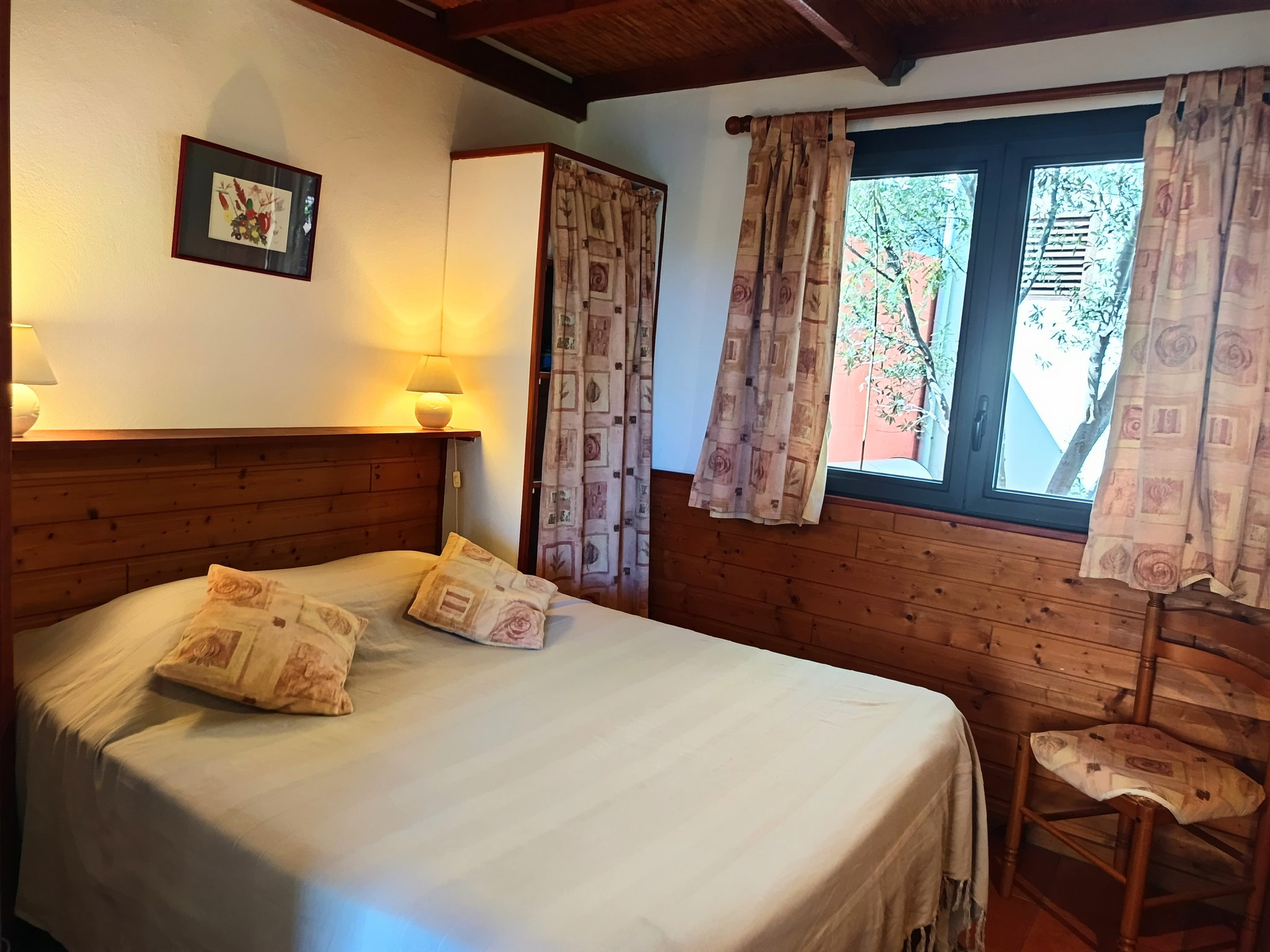 Double bedroom with wooden headboard and warm lighting, Bungalow 6, furnished bungalow Le Cardinal des Grands Bleus