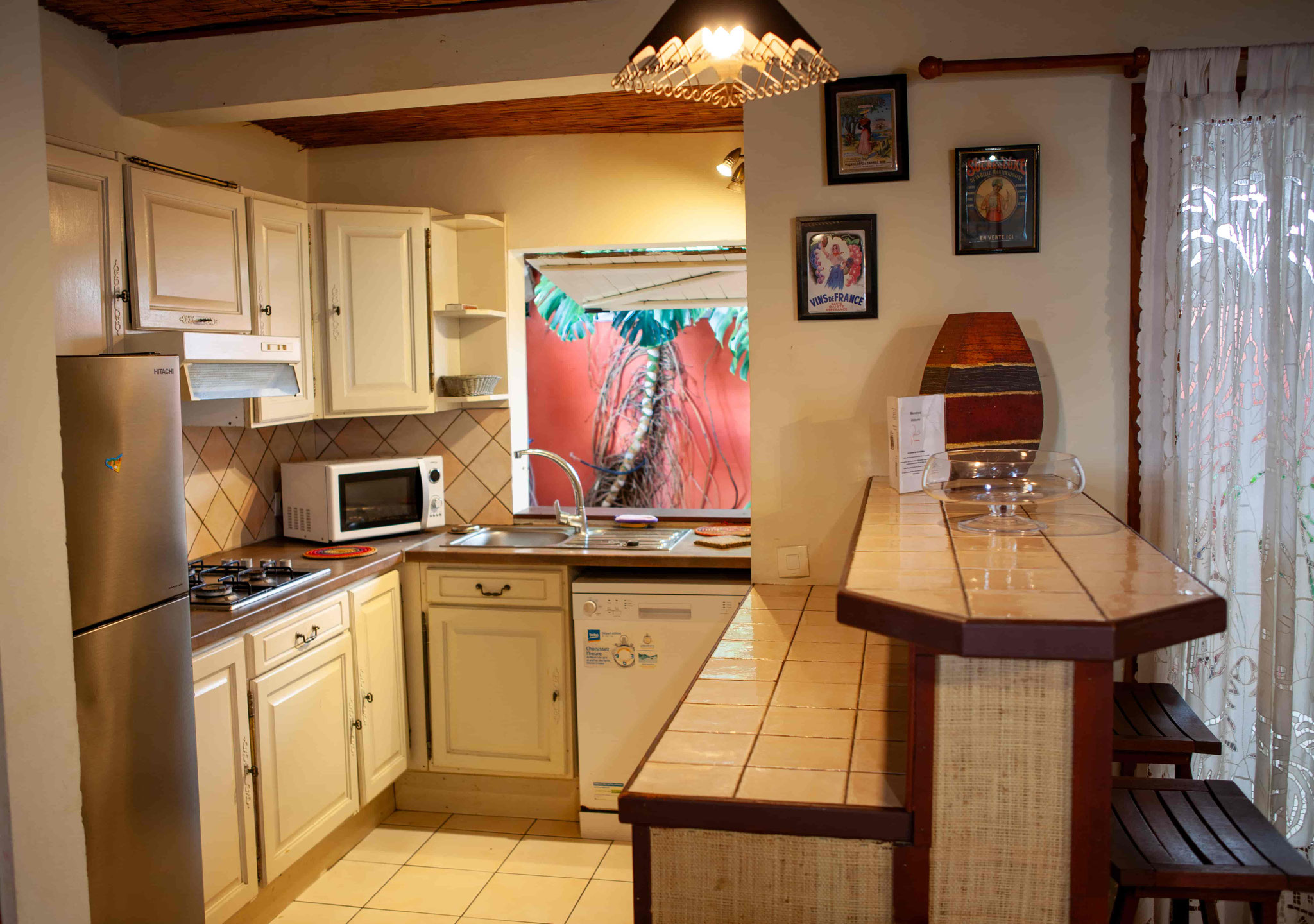 Fully equipped kitchen with white units, island and colourful artwork, Bungalow 10 T4, Saint-Leu Réunion