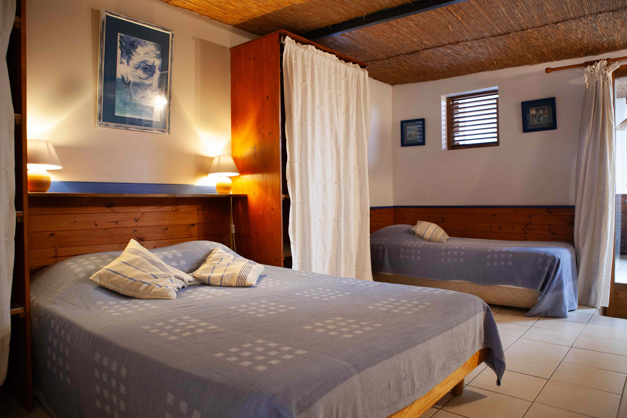 Double bedroom with grey bedding and white curtains, Bungalow 10 T4, furnished holiday rental Saint-Leu