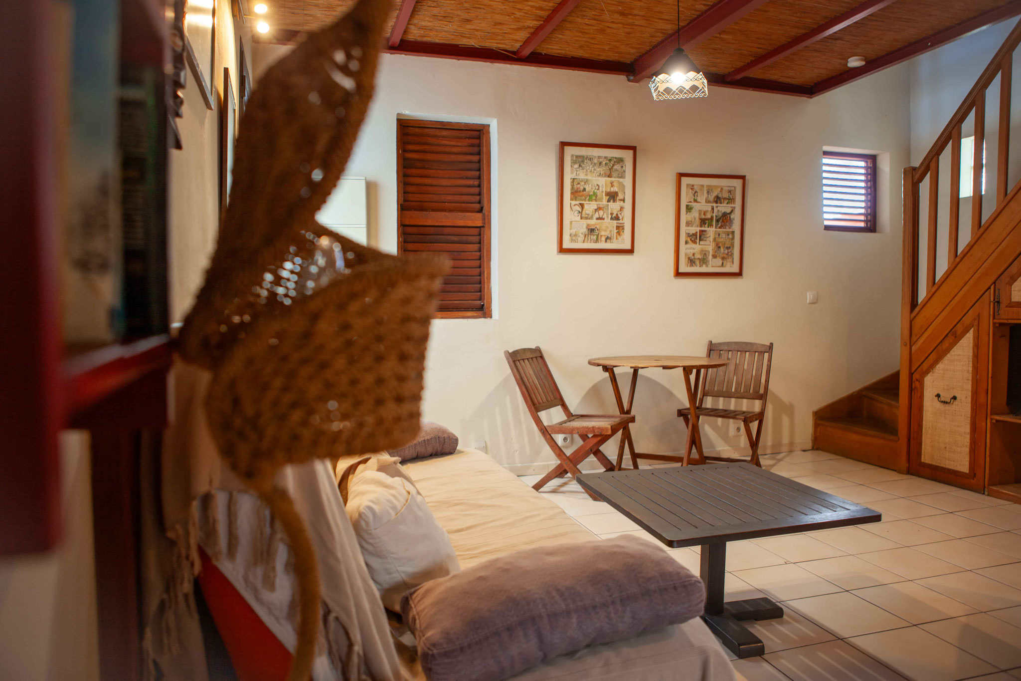 Living room bungalow No.10 – sofa bed, coffee table, staircase to first floor, wooden roof structure