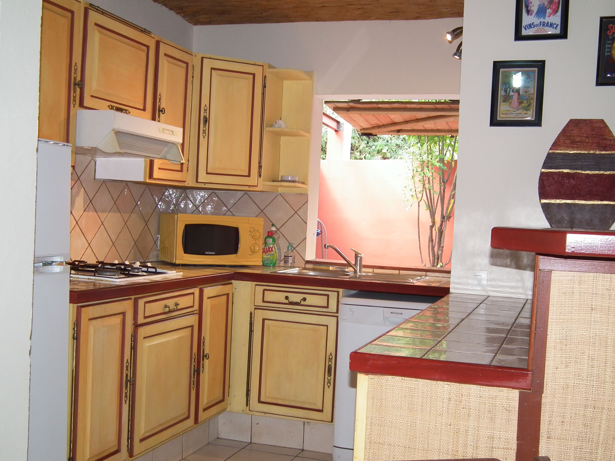 Cuisine bungalow n°10 – meubles clairs, lave-vaisselle, réfrigérateur, mur rouge