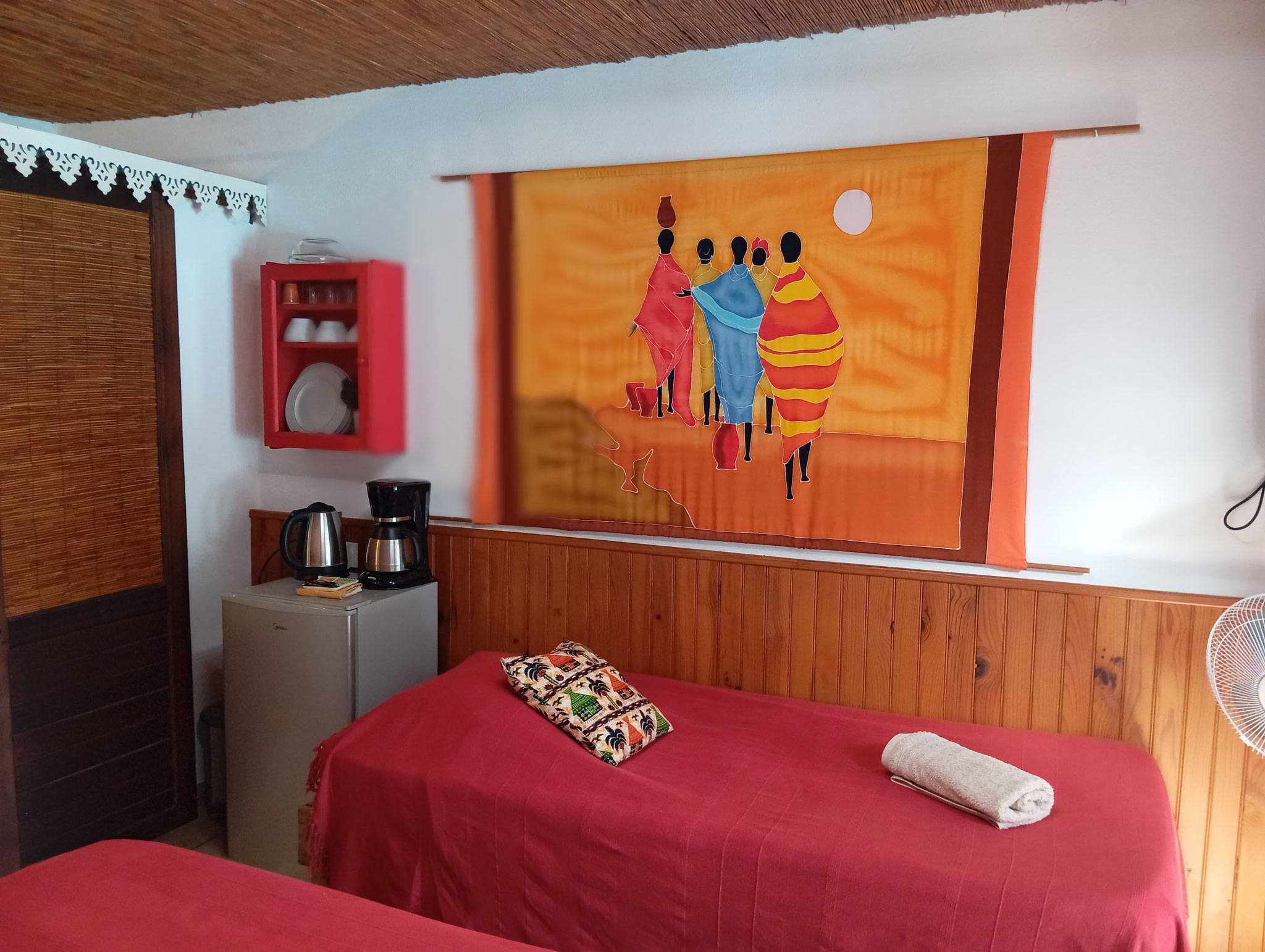 Bedroom with vibrant African wall art and red bedding, Room 5, bungalow rental Reunion Island