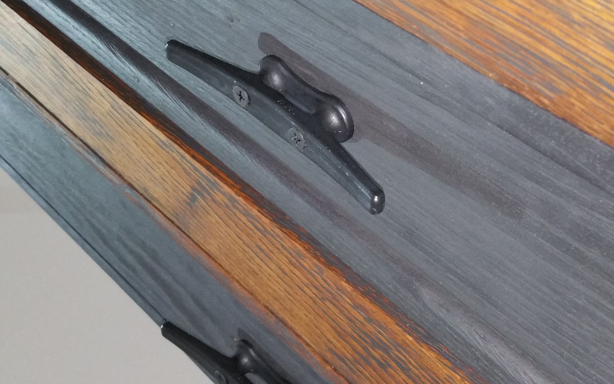 Gleicher Schrank, Detailaufnahme von länglichen Griffen auf dunklen Flächen