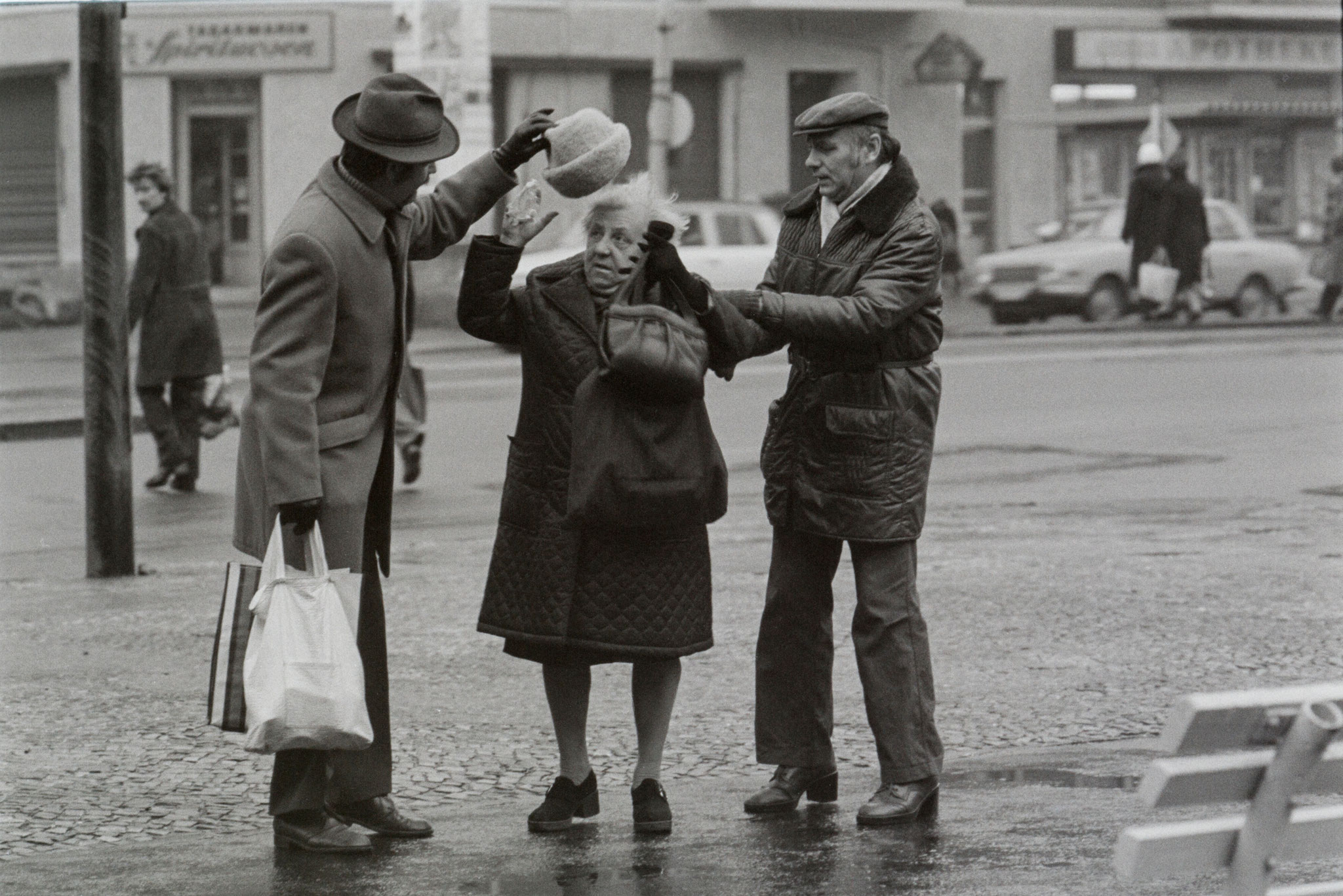 Eine ältere Dame ist bei Glatteis gestürzt. Zwei Passanten haben beim Aufstehen geholfen und geben ihr Handtasche und Hut zurück. Aufnahme von 1973. Foto: DDR Fotoerbe / Michael Richter