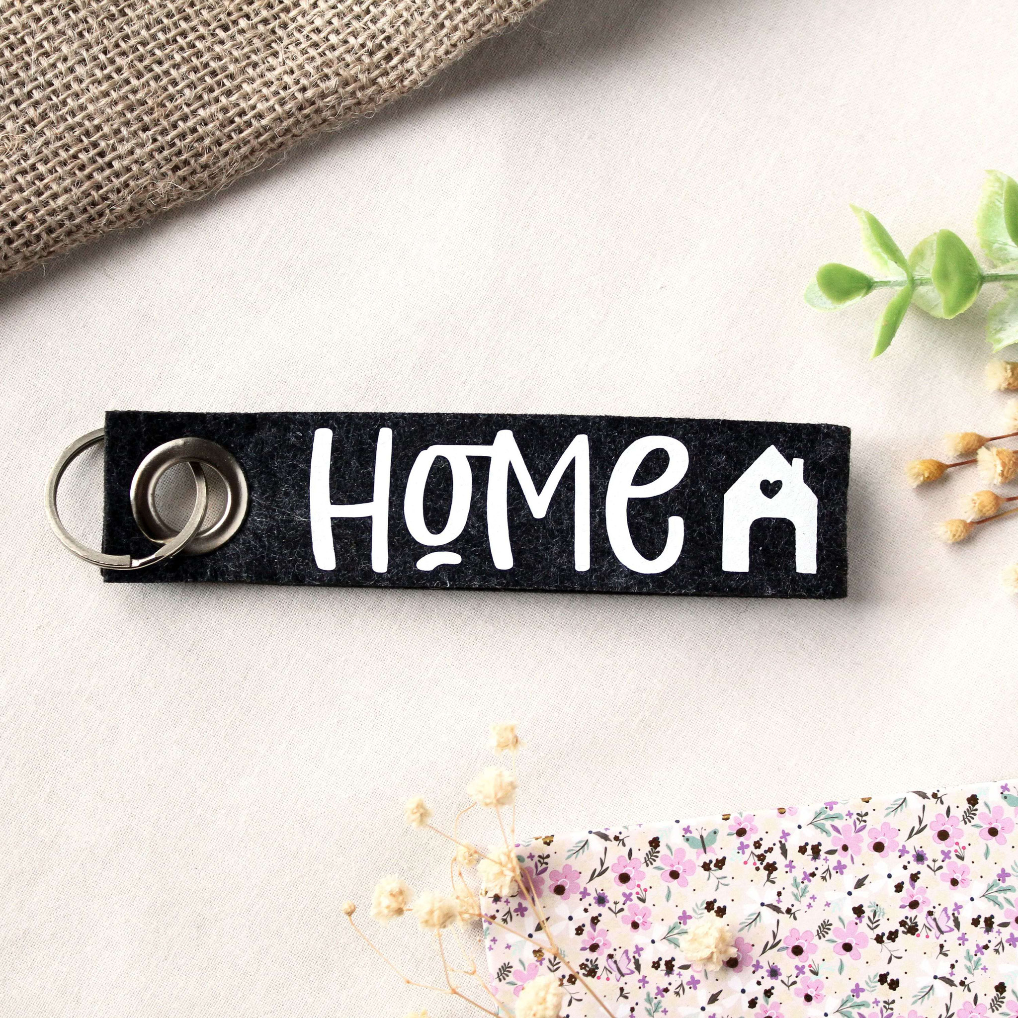 Schlüsselanhänger aus schwarzem Filz mit „HOME“-Print und Herzhaus-Symbol – liebevolles Geschenk für Zuhause.