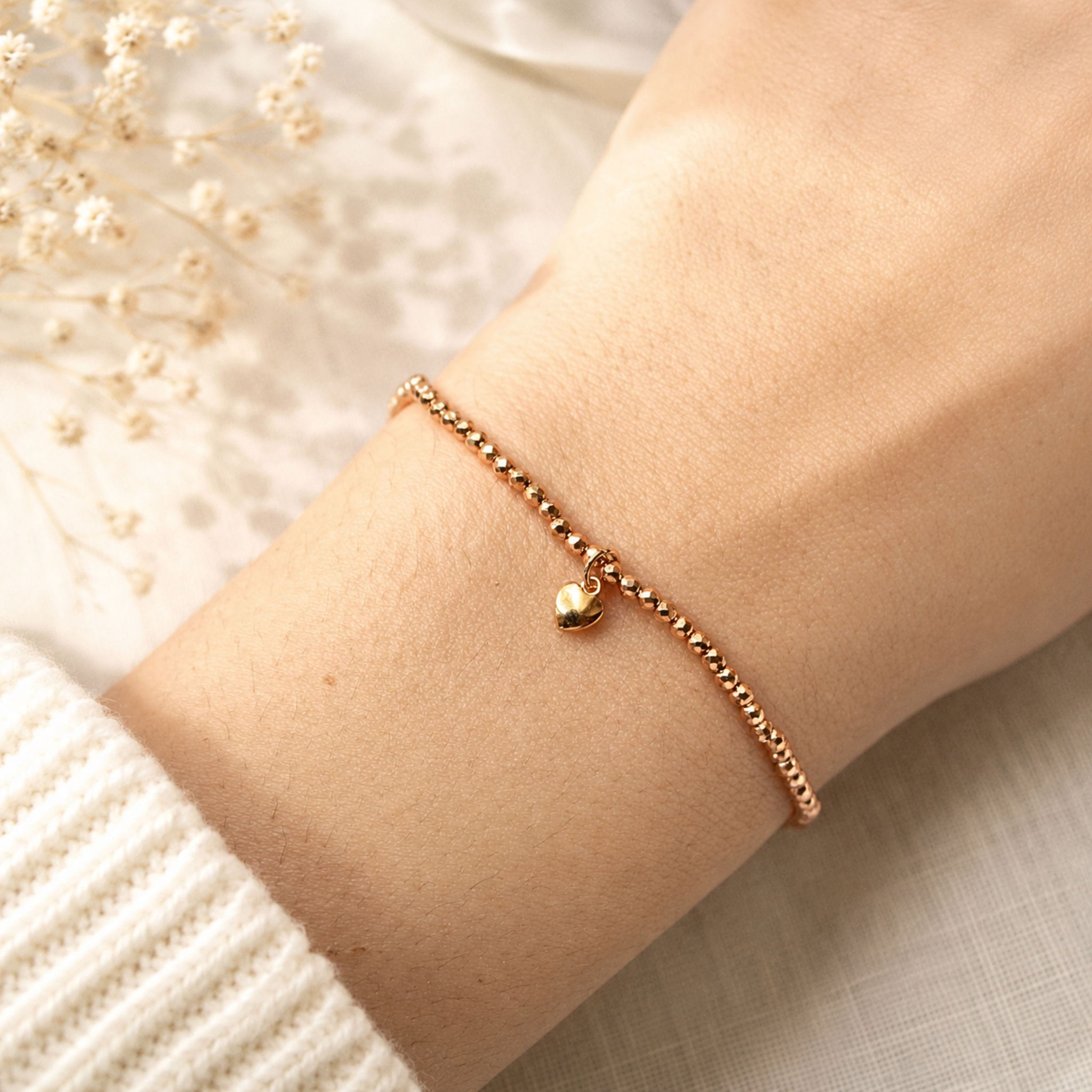 Roségoldenes Perlenarmband mit Herzanhänger am Handgelenk