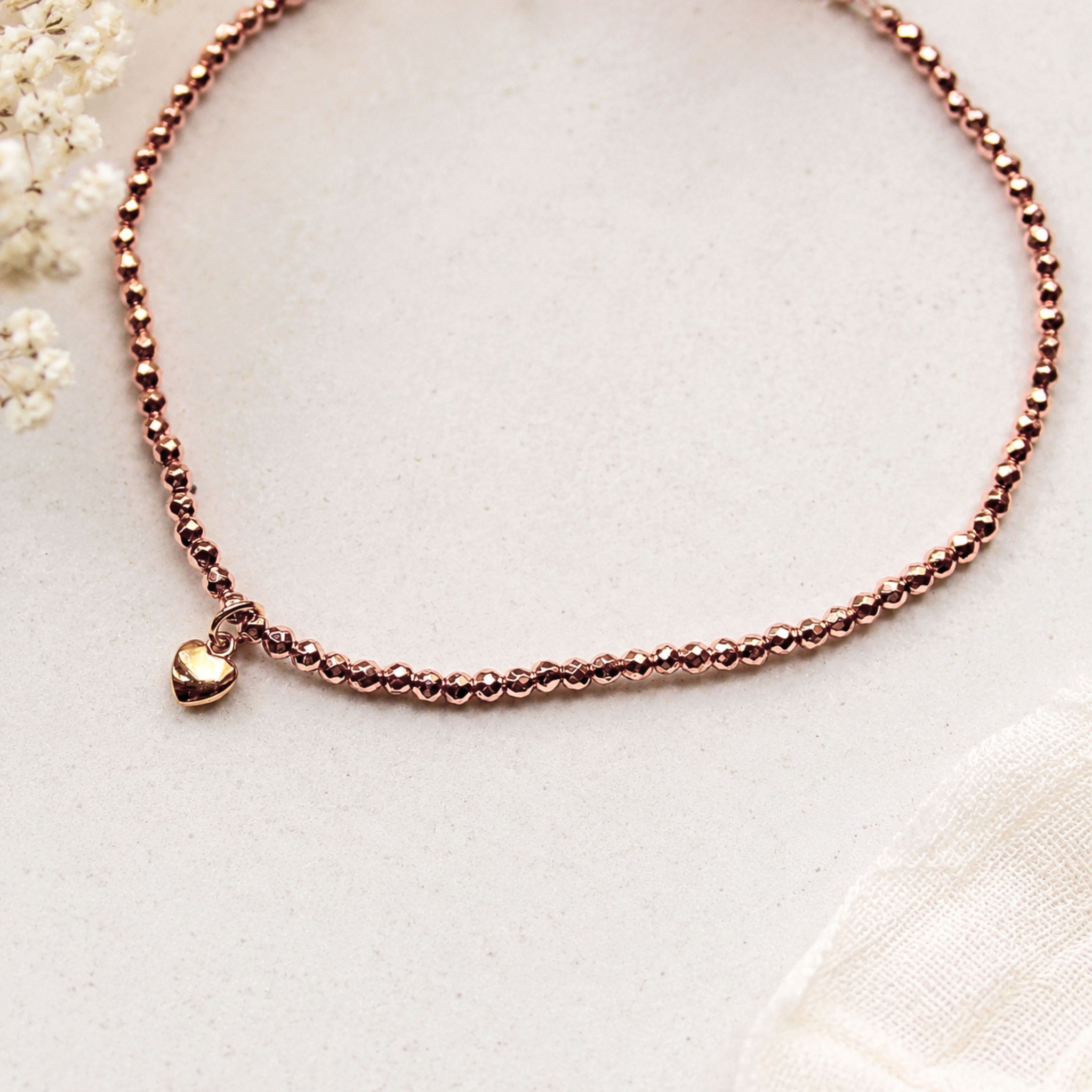 Roségoldenes Perlenarmband mit Herzanhänger.