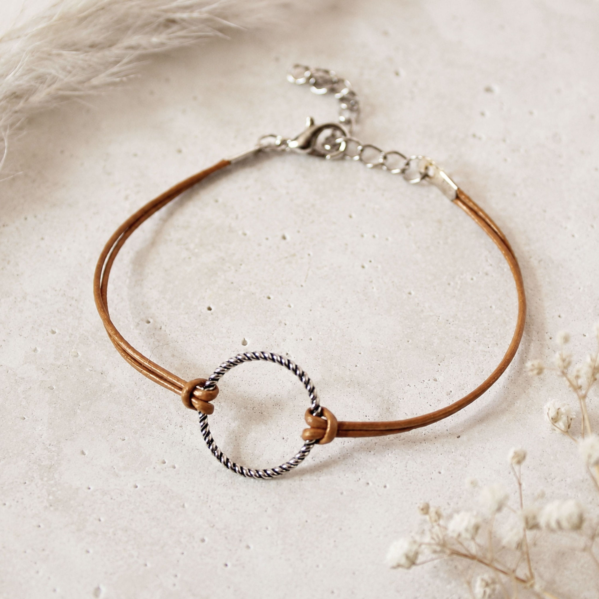 Hellbraunes Lederarmband mit silbernem Ringelement und Karabinerverschluss.