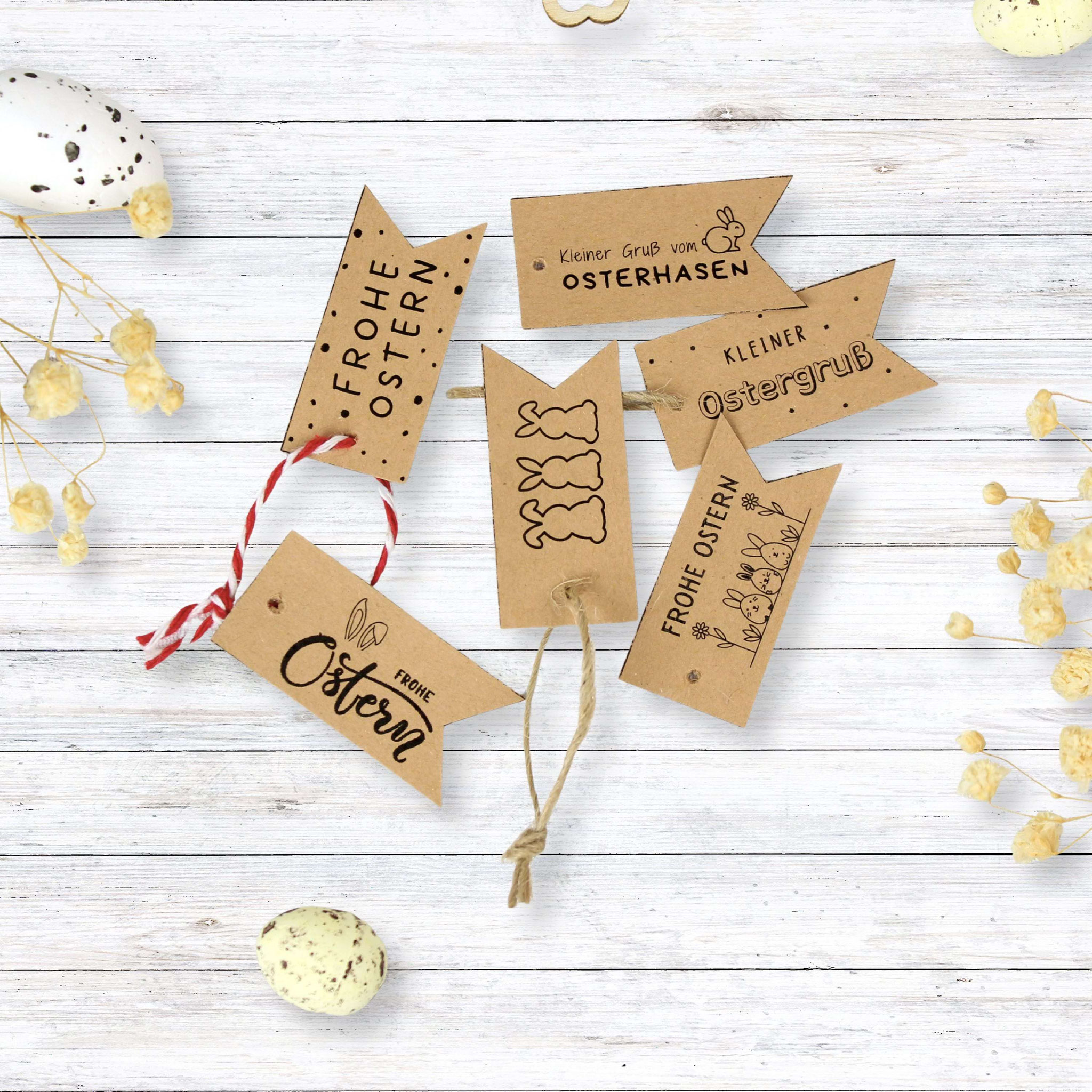 Oster-Geschenkanhänger aus Kraftpapier mit Hasenmotiven, dekoriert mit Eiern und Frühlingsblüten für DIY‑Geschenke.