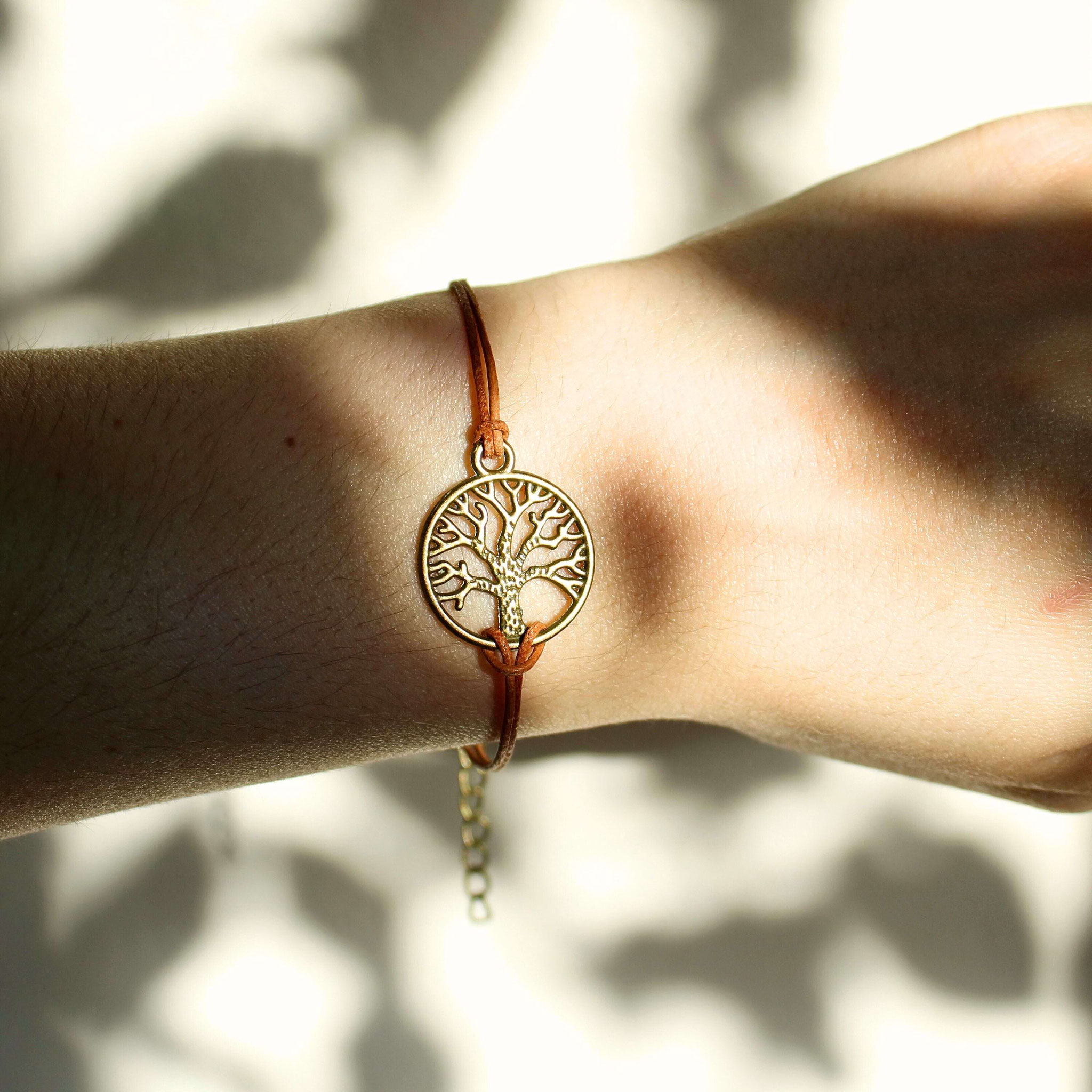 Lebensbaum-Armband aus braunem Leder am Handgelenk, stimmungsvoll im natürlichen Licht.