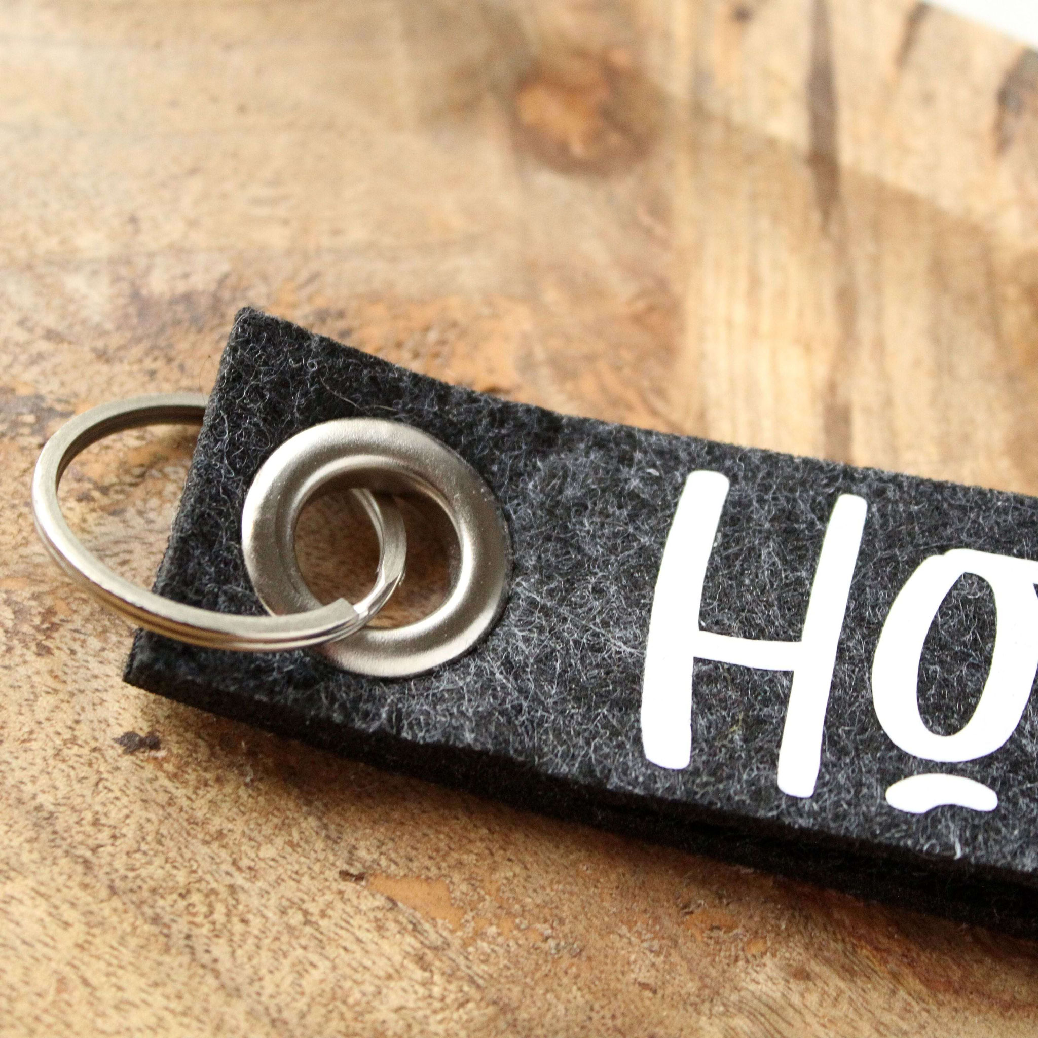 Detailaufnahme eines schwarzen Filz-Schlüsselanhängers mit „Home“-Print – stilvolles Accessoire für Schlüssel oder Geschenke.