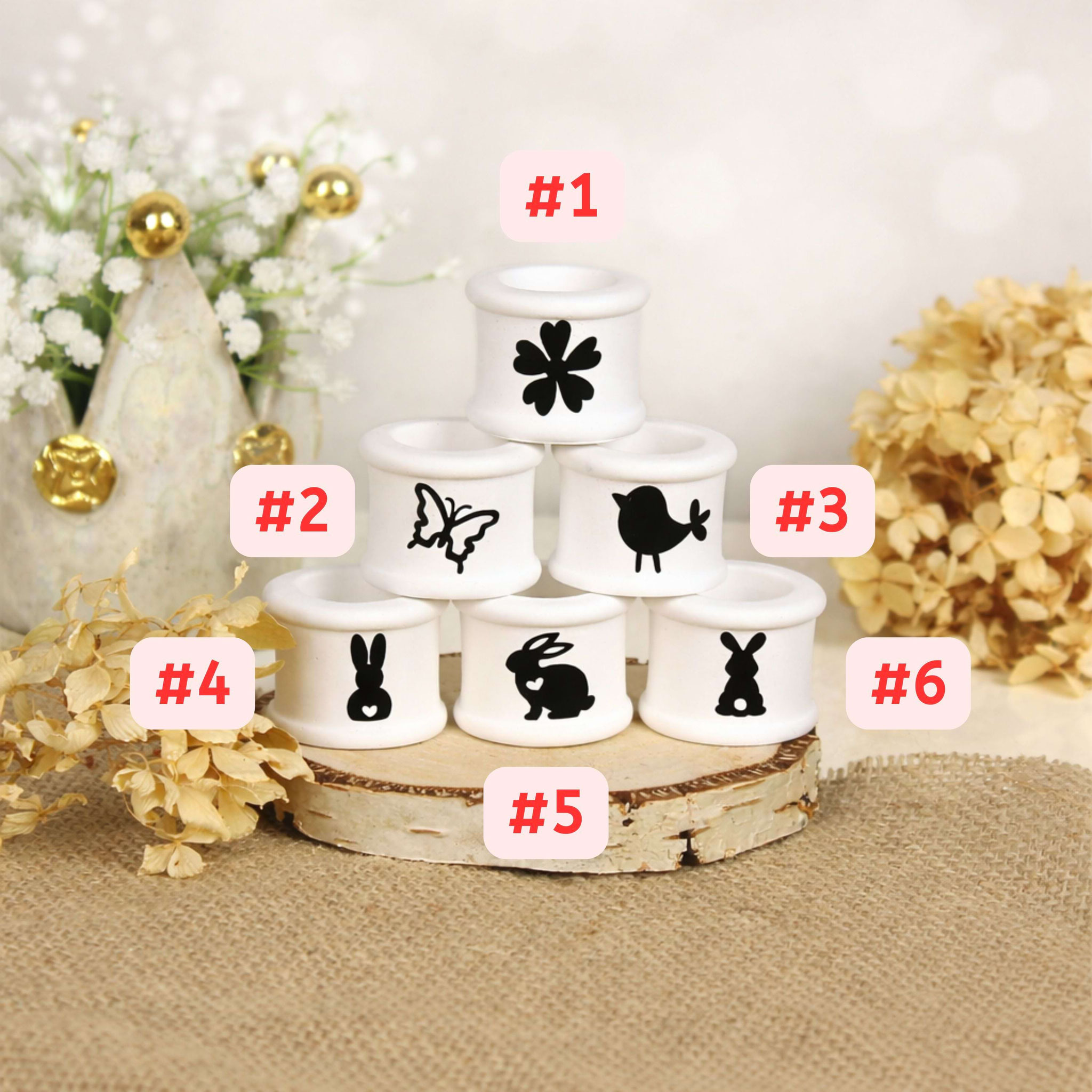 Weiße Mini‑Kerzenhalter mit Frühlings- und Ostermotiven auf Holztablett, dekorativ arrangiert zur Produktpräsentation.