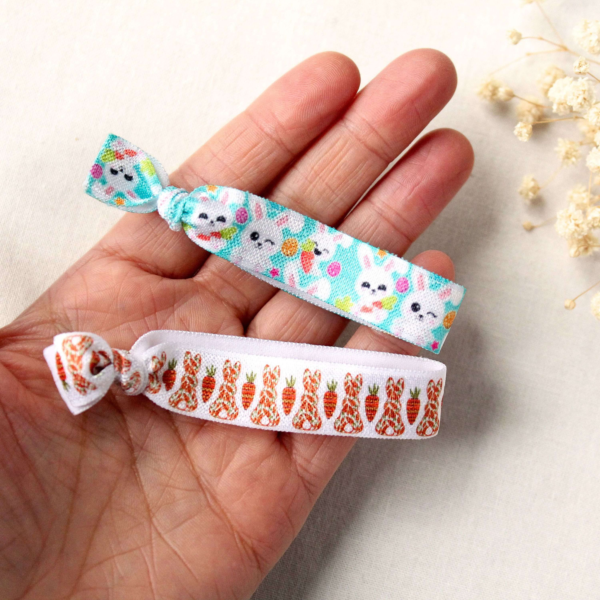 Zwei elastische Osterarmbänder mit Hasen- und Karottenmotiven in der Hand – Detailfoto zur Größen- und Materialdarstellung.