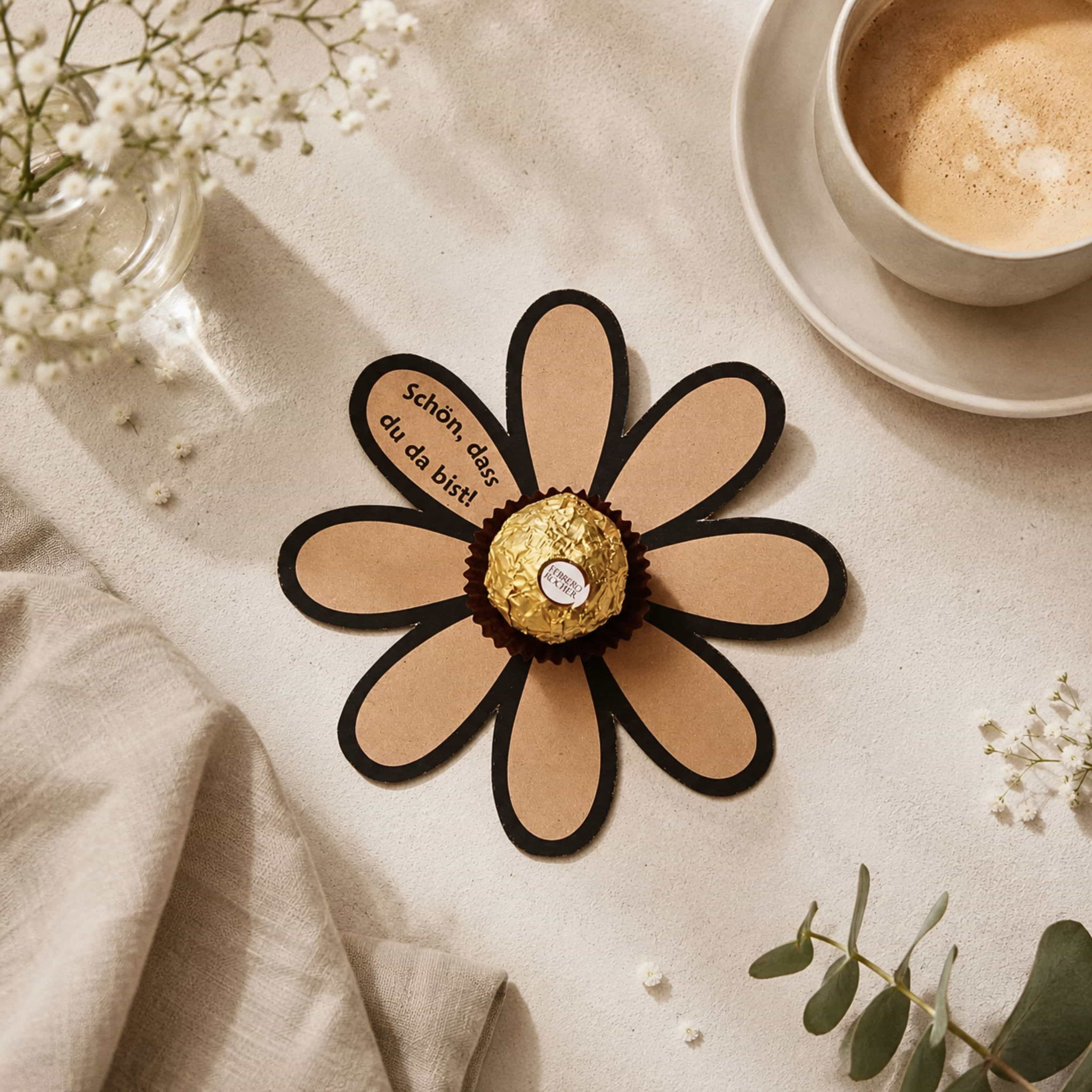 Papierblume mit Ferrero Rocher und „Schön, dass du da bist!“ als liebevolles DIY‑Gastgeschenk in gemütlicher Tischszene.