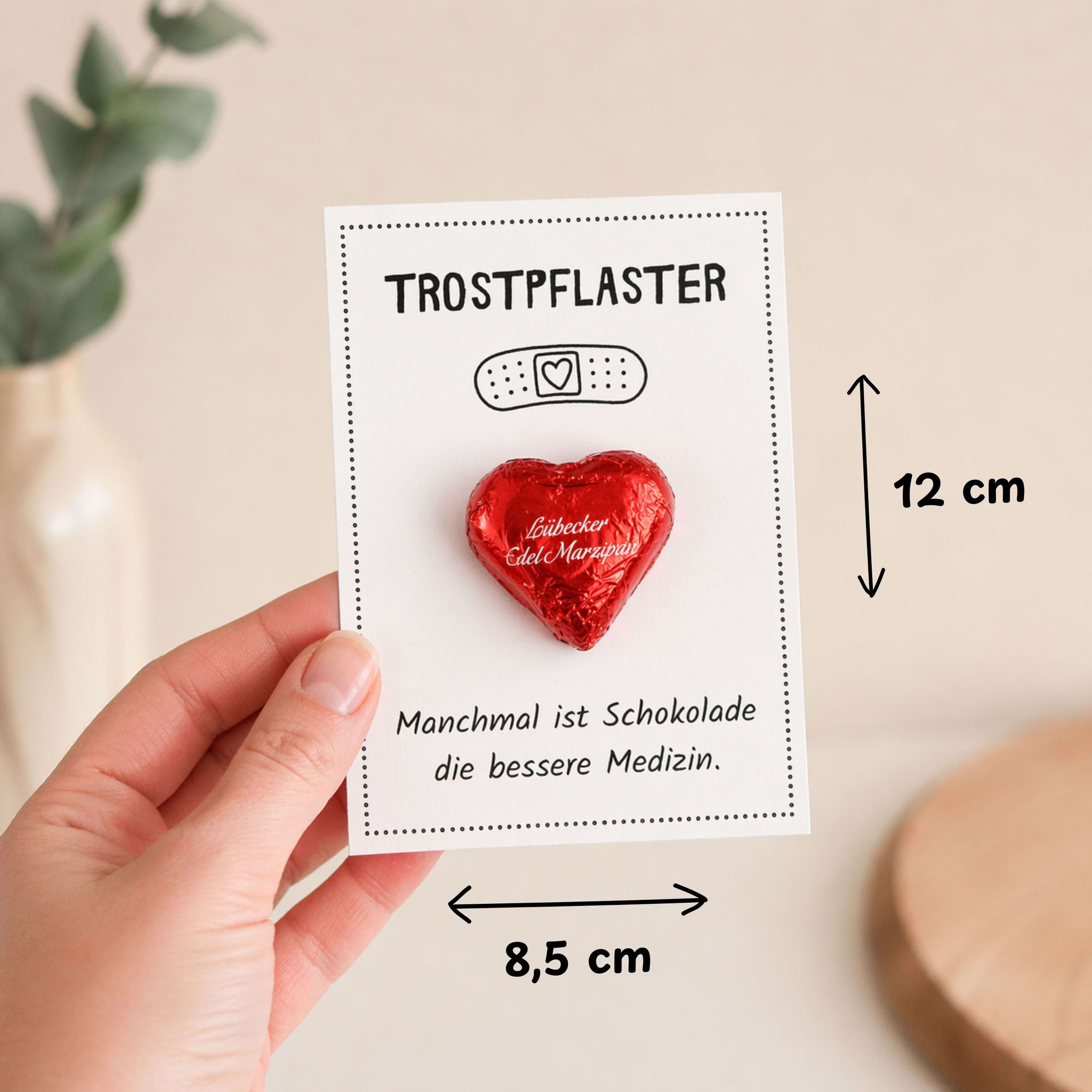 Hand hält Trostpflaster‑Karte mit Herzschokolade, DIY‑Aufmunterungsgeschenk zum Ausdrucken.