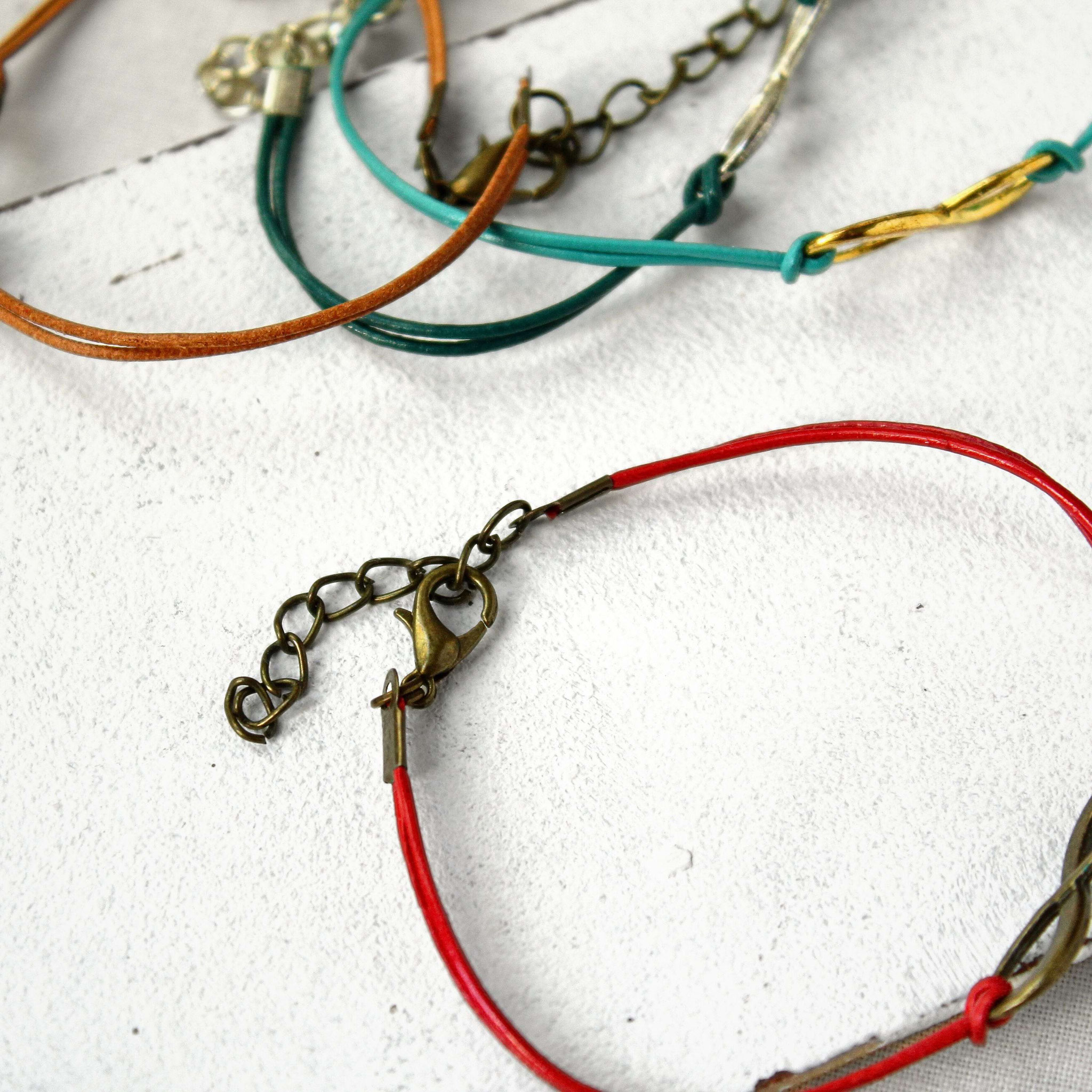 Handgefertigte Lederarmbänder in kräftigen Farben mit Metallverschlüssen, präsentiert als Auswahl moderner, personalisierbarer Schmuckbänder.