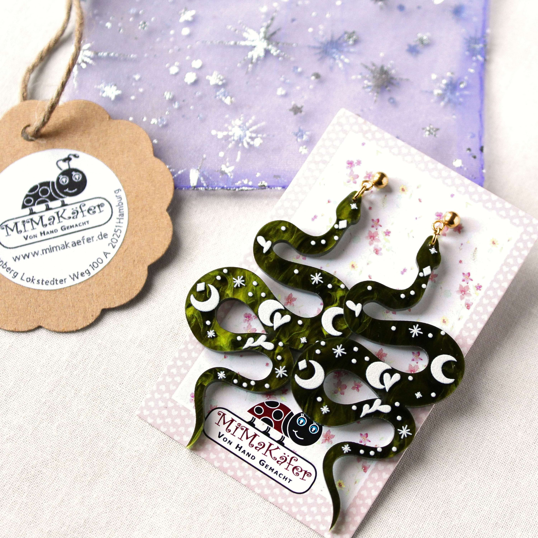 Grüne Schlangenohrringe mit Symbolen auf Markenkarte „MiMaKäfer“ – Produktfoto für handgemachten Schmuck.