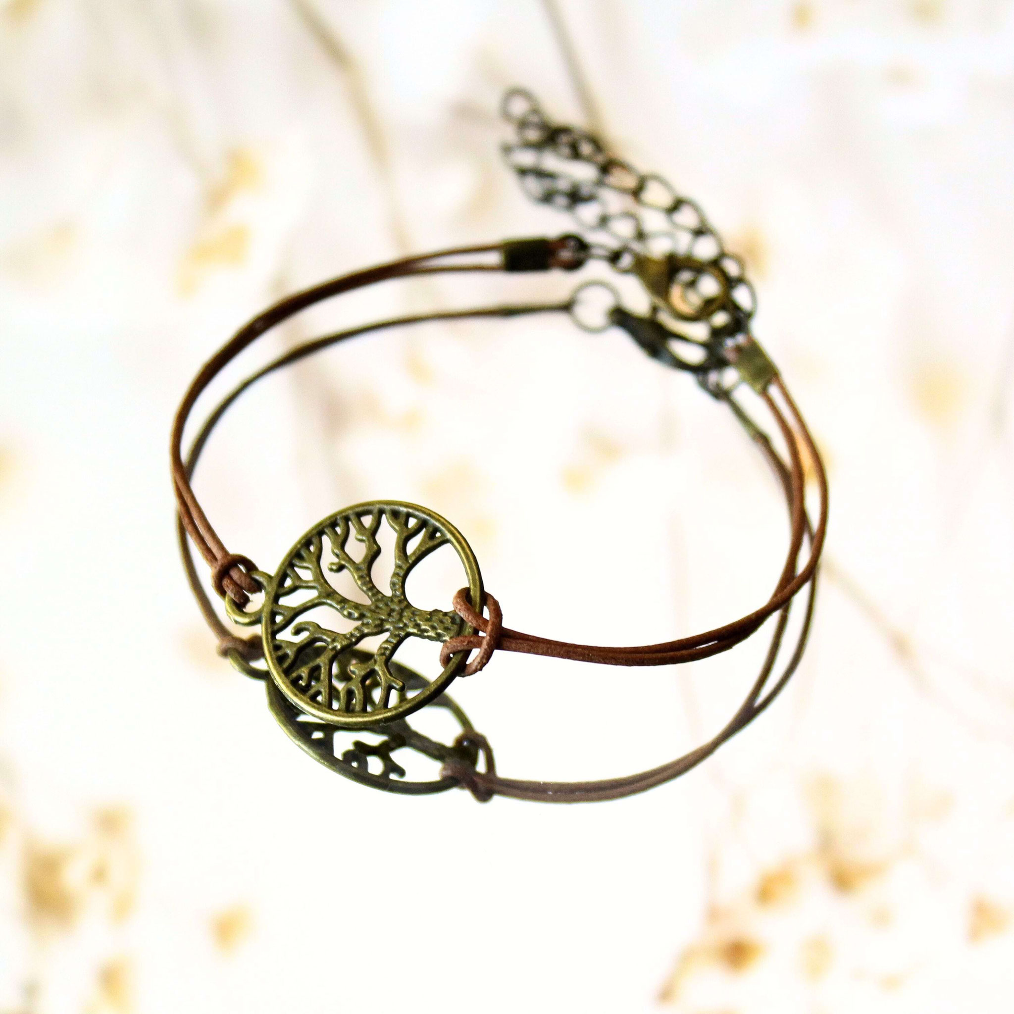 Handgemachtes Lederarmband mit Lebensbaum-Anhänger, dekorativ auf hellem Hintergrund.
