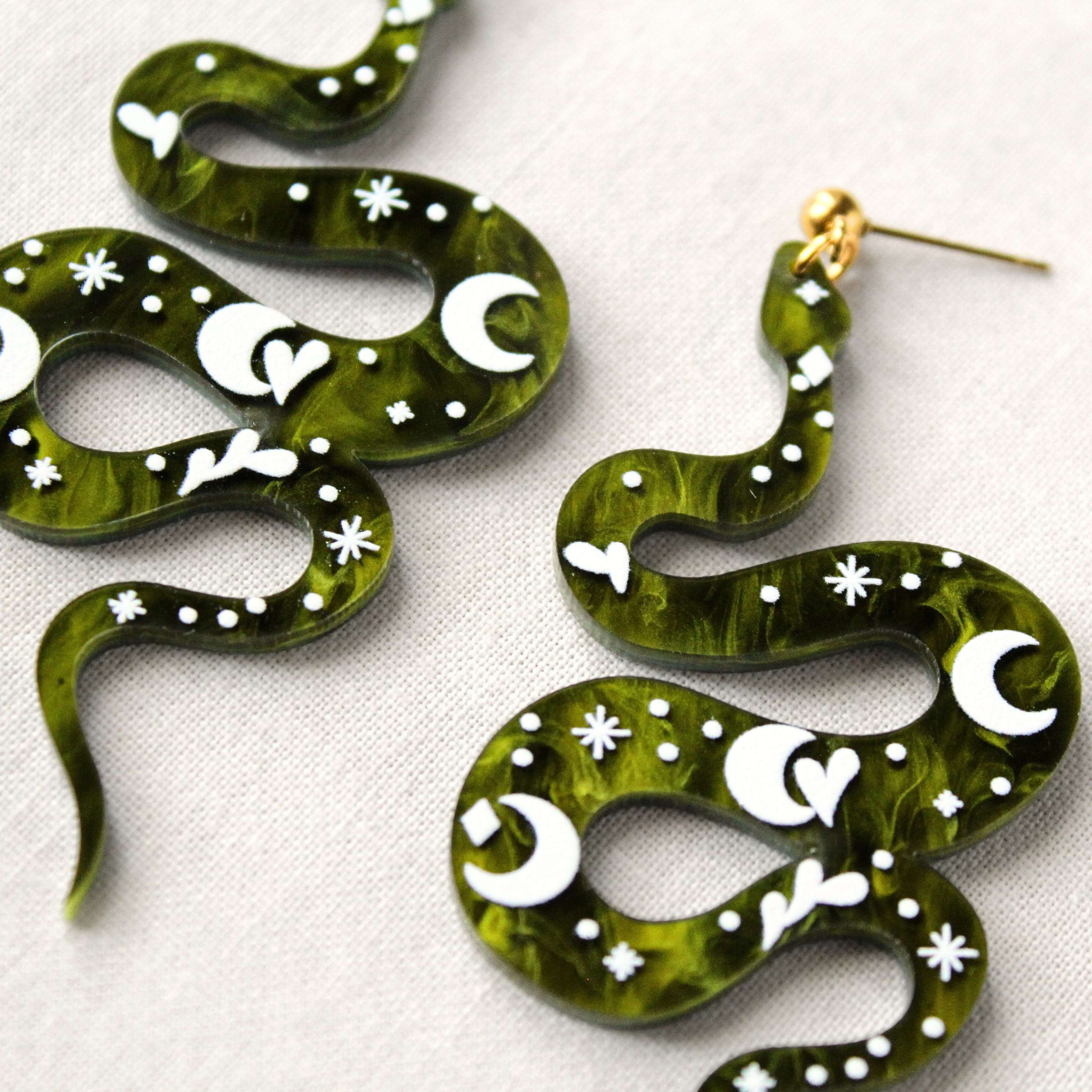 Grüne Schlangenohrringe mit goldfarbenem Stecker und mystischen Symbolen.