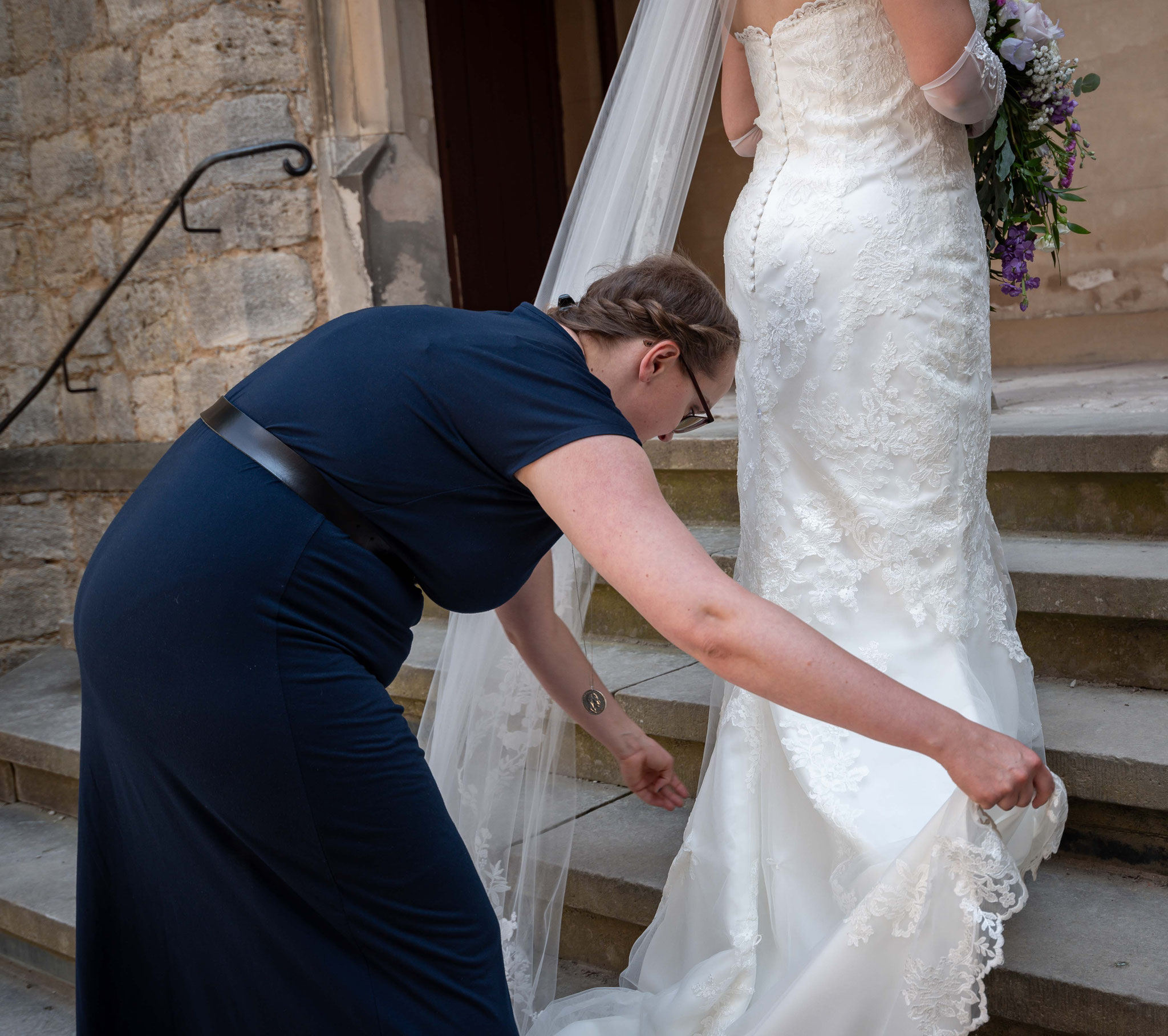Brautjungfer und Braut richten das Kleid