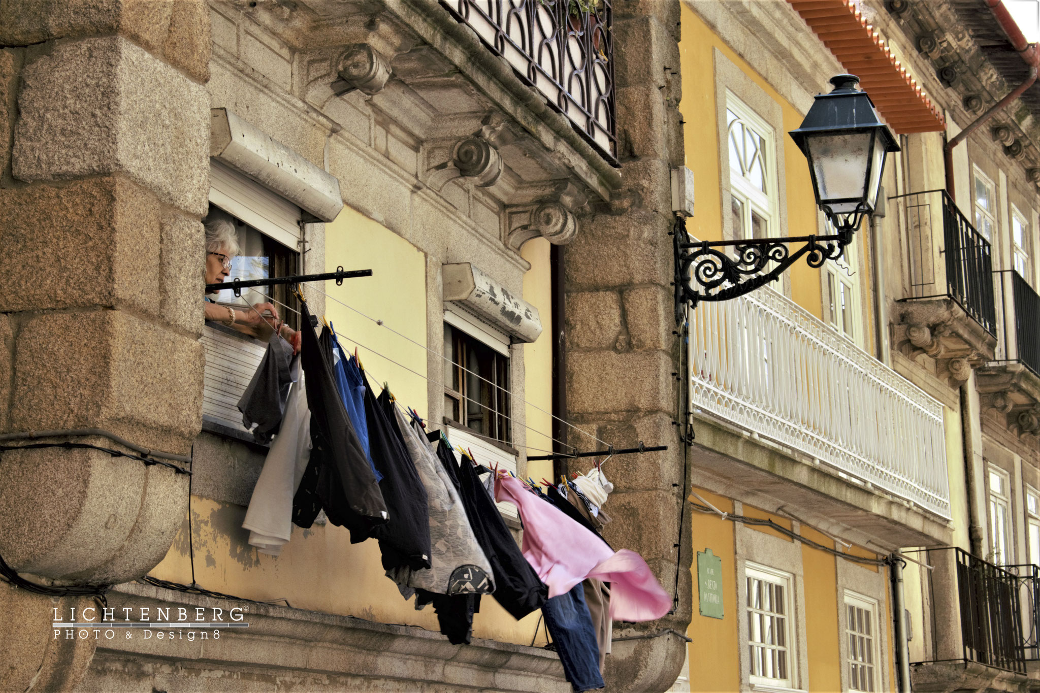 Portugisische Frau nutzt das kleinste Fenster dieser historischen Gasse für ihre Wäsche, PT