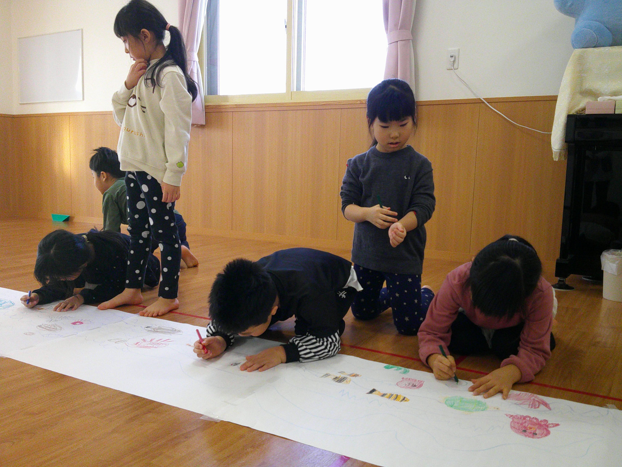 折り紙の船を「海の上で浮かばせたい」の発想から海の中を描き始めた年長さん。
