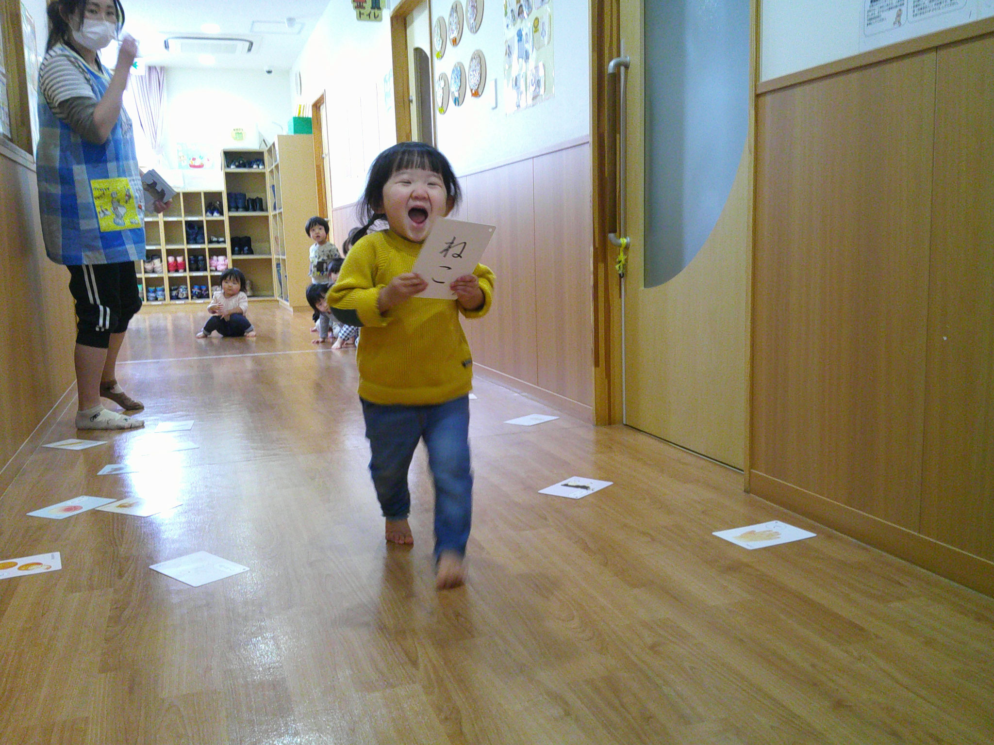 1歳児クラスは廊下でカルタとりごっこ。