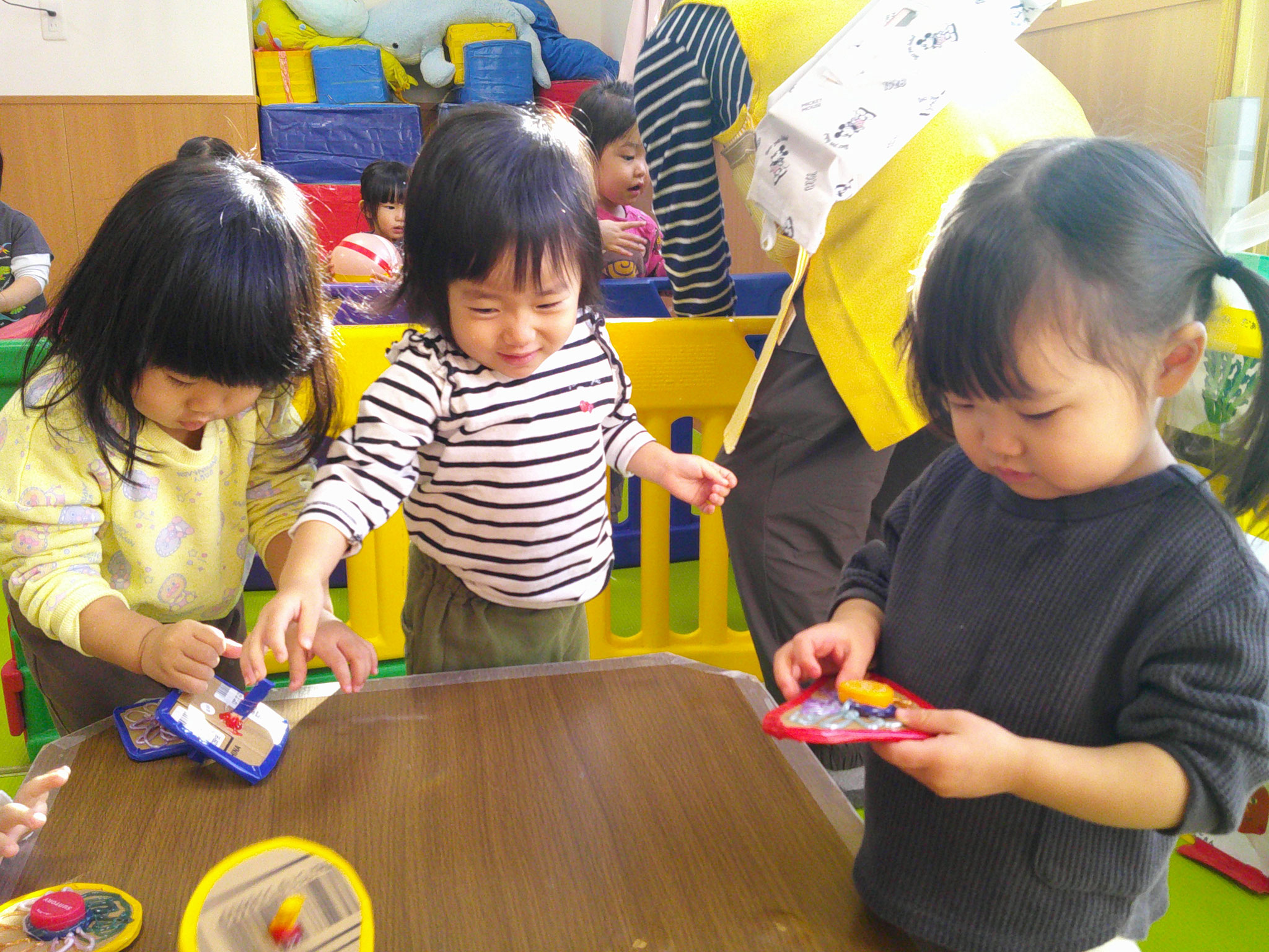 1歳児クラスでお正月遊び。手作りのコマをまわしてます。