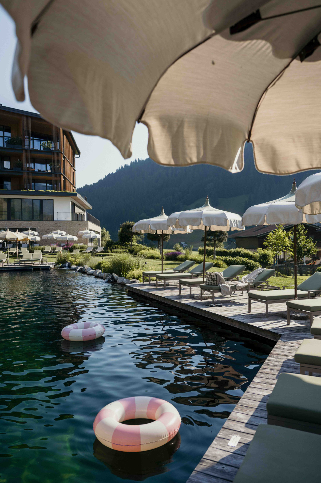 Badeteich mit Liegestühlen und Badesteg - NESSLERHOF in Großarl • 5-Sterne-Wellnesshotel im Salzburger Land