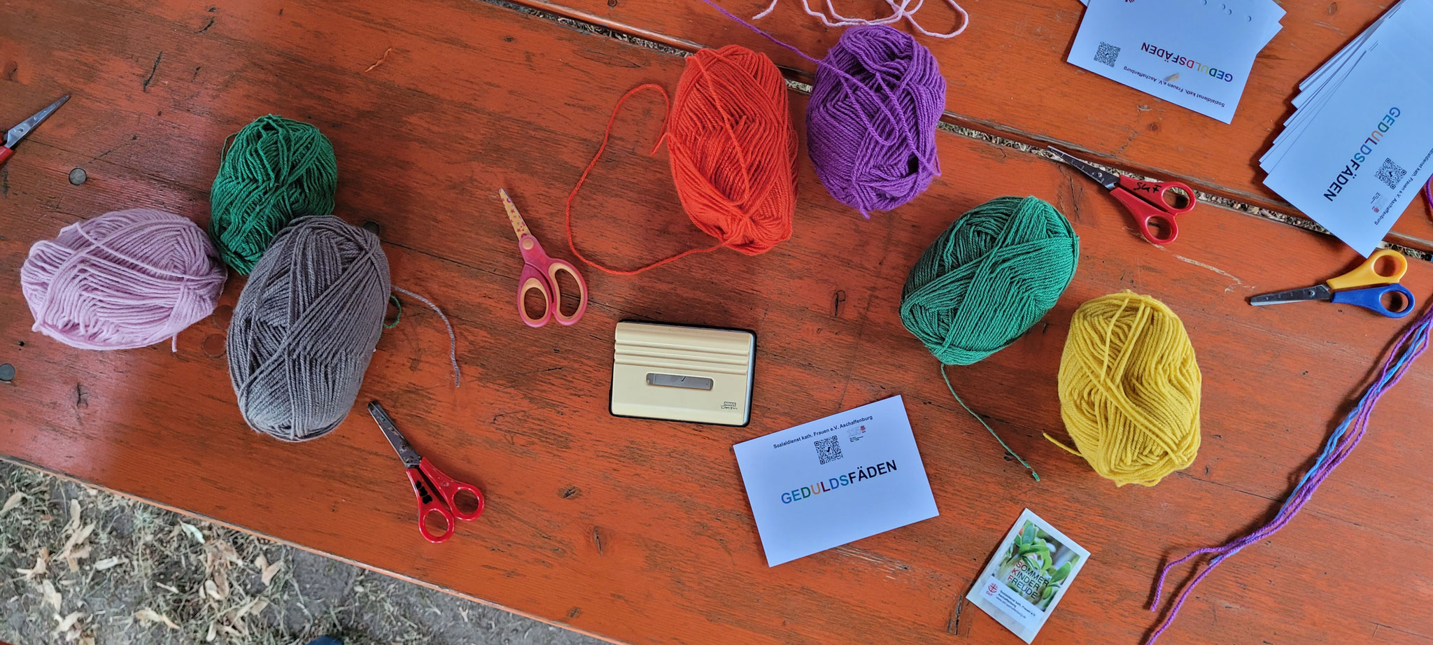 Bunte Wollknäuel liegen auf einem Tisch 
