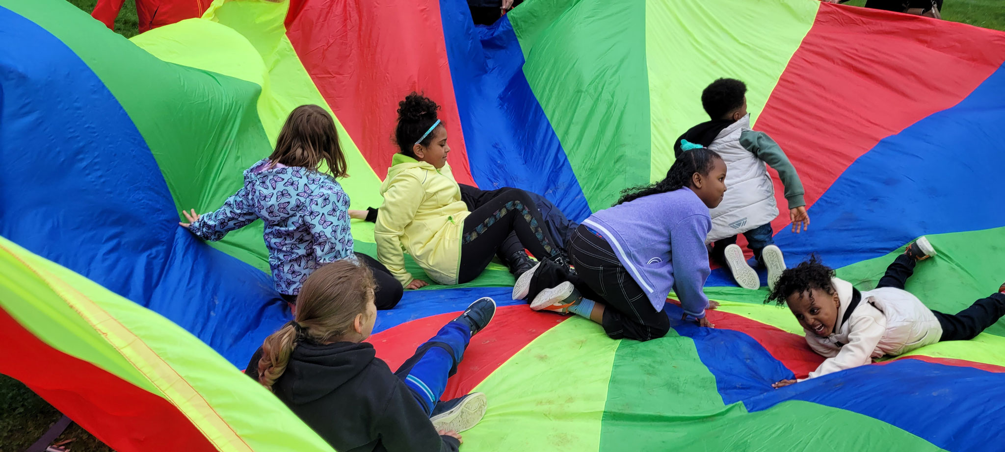 ein buntes Schwungtuch und darauf spielende Kinder
