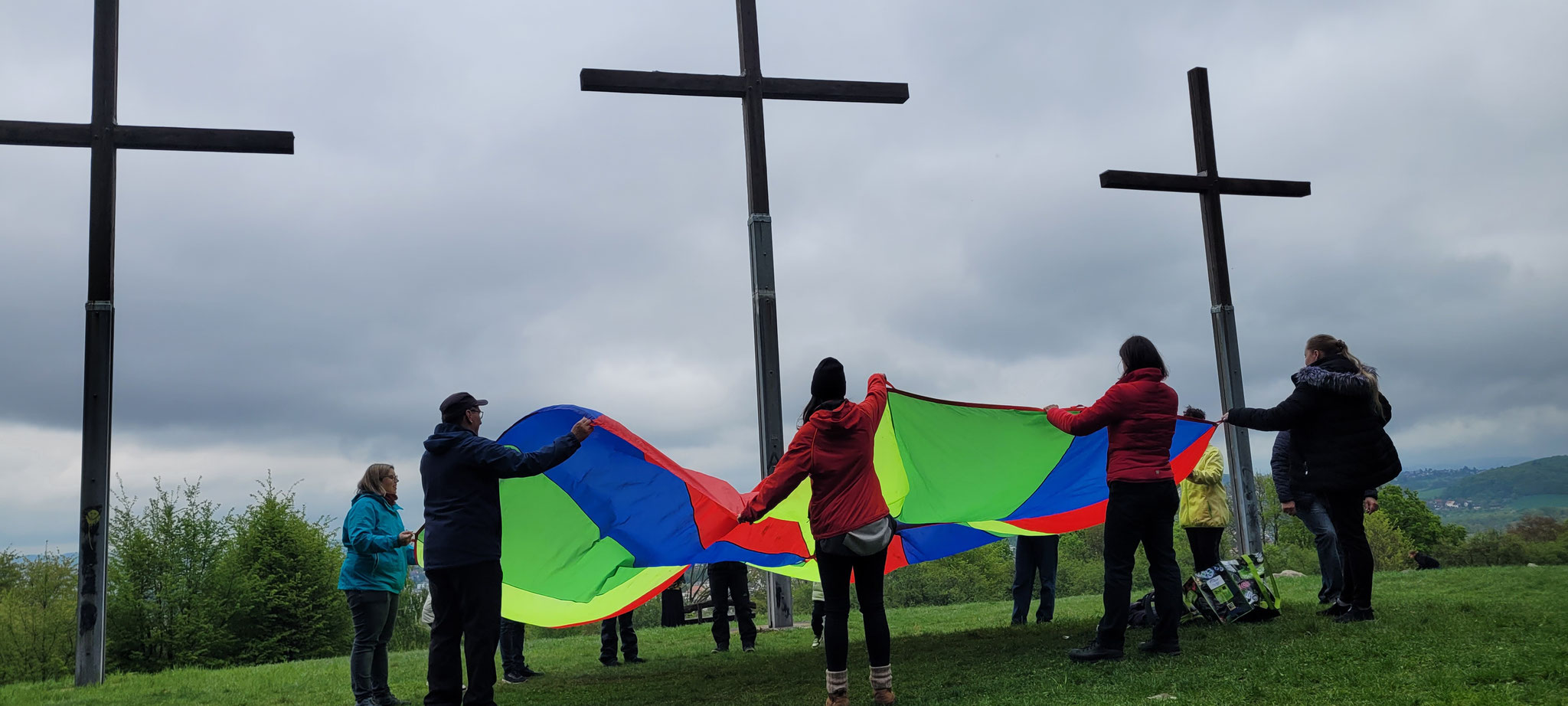 ein buntes Schwungtuch an den Rändern stehen Kinder und Erwachsene
