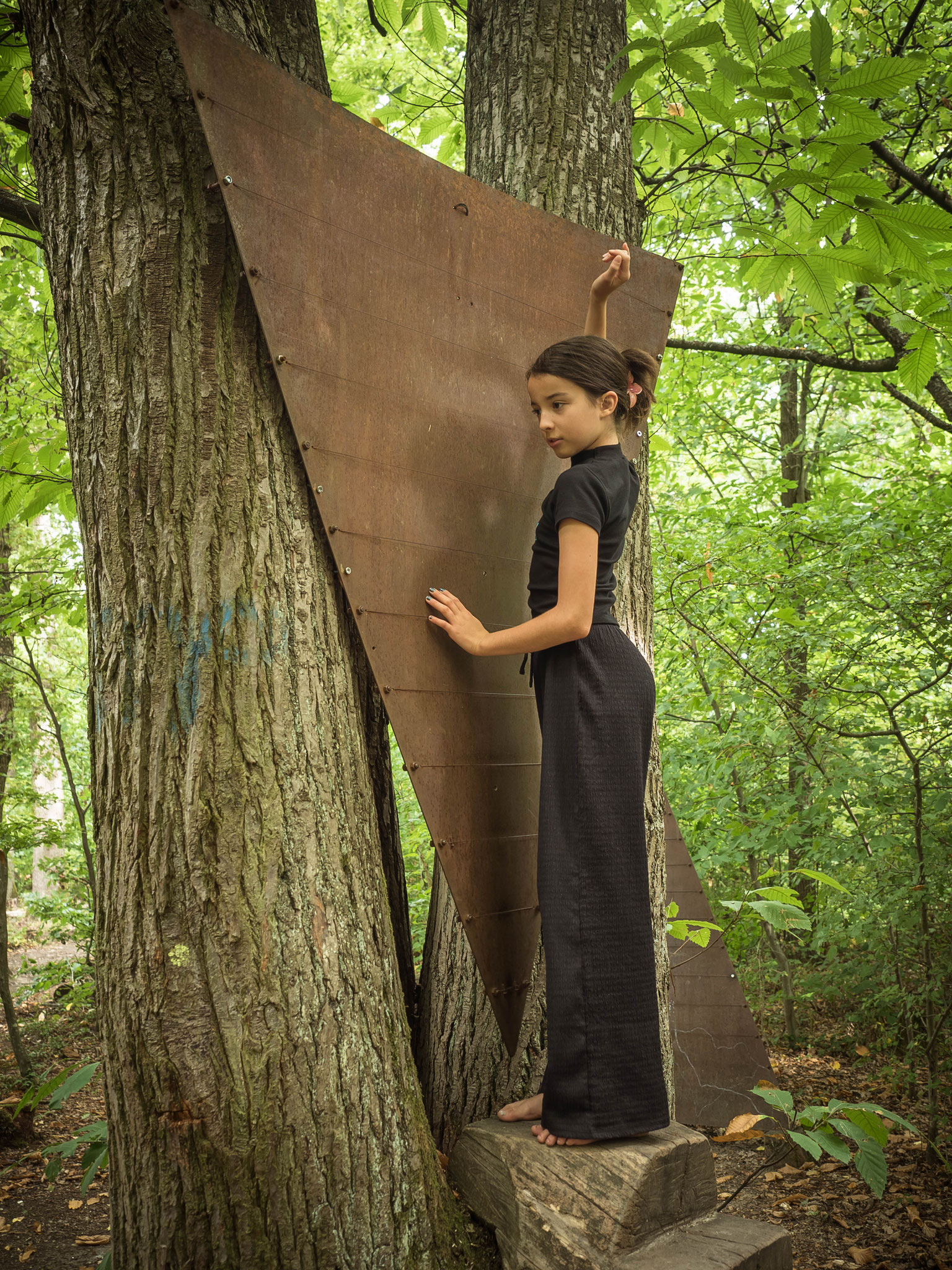 Ein Mädchen steht vor einer Metallwand auf dem Baum