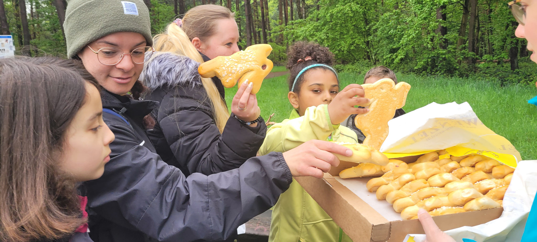 Erwachsene und Kinder die sich Hefehasen aus einem Karton nehmen