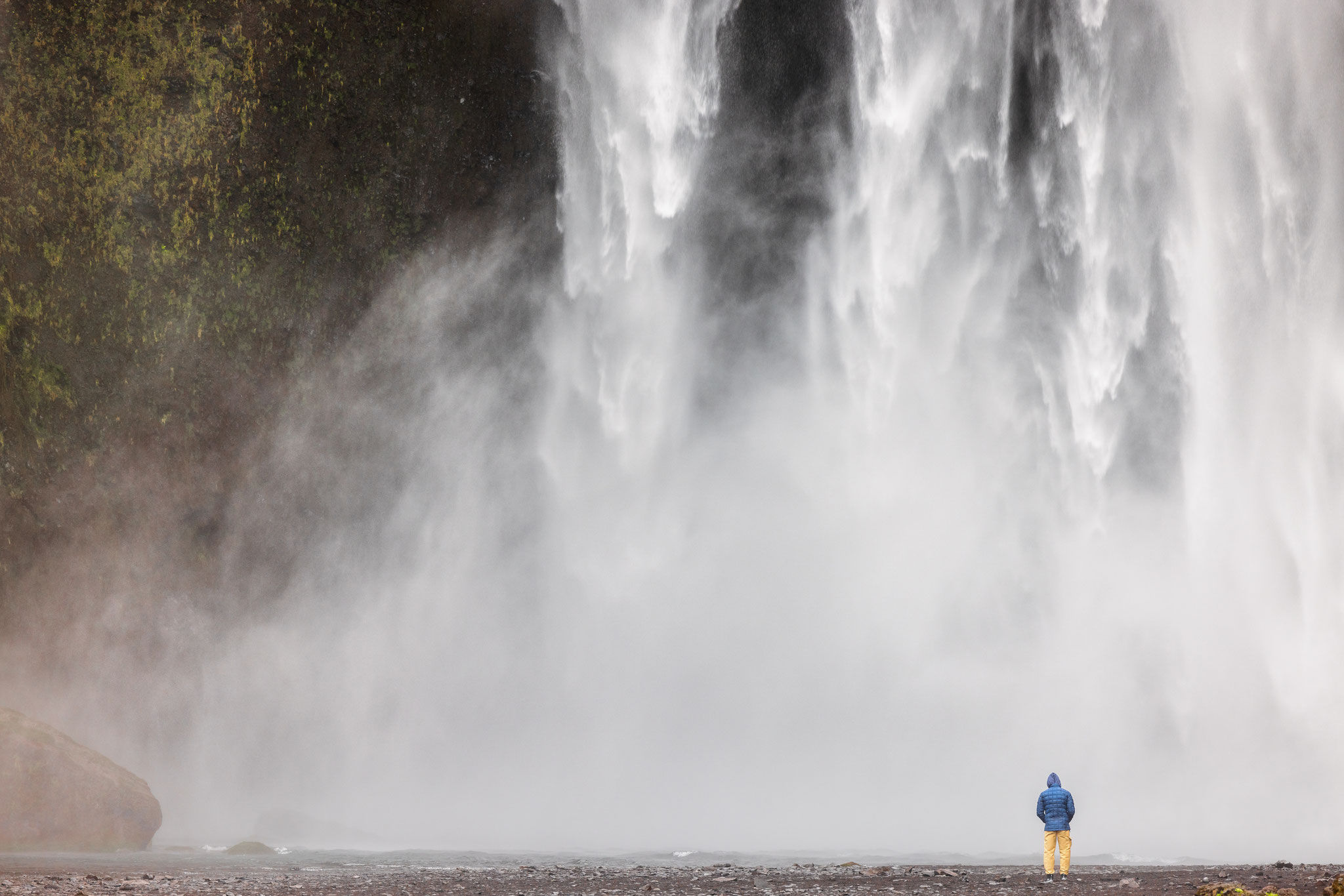 Skogafoss mit Mensch. Der hier die Dimensionen des 60 Meter hohen Wasserfalls verdeutlicht.