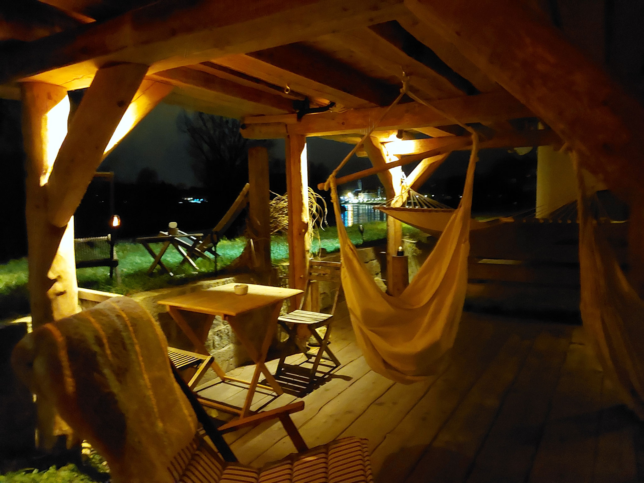 Das Holzdeck unter der Stelzensauna mit Hängematte und Sitzsäcke
