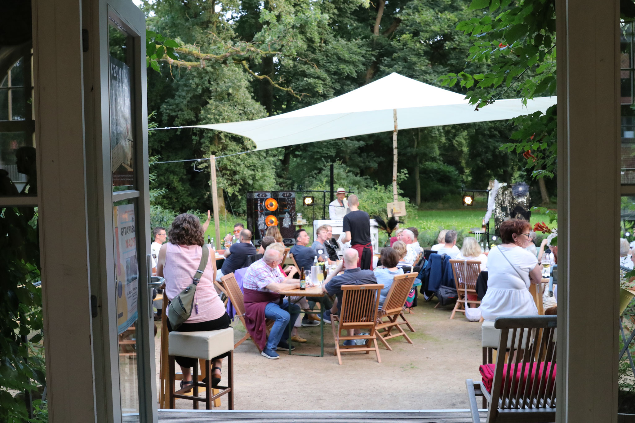 Gäste genießen Konzert mit Thomas Kübler bei kühlen Getränken und Grill im Schlosspark Krumke