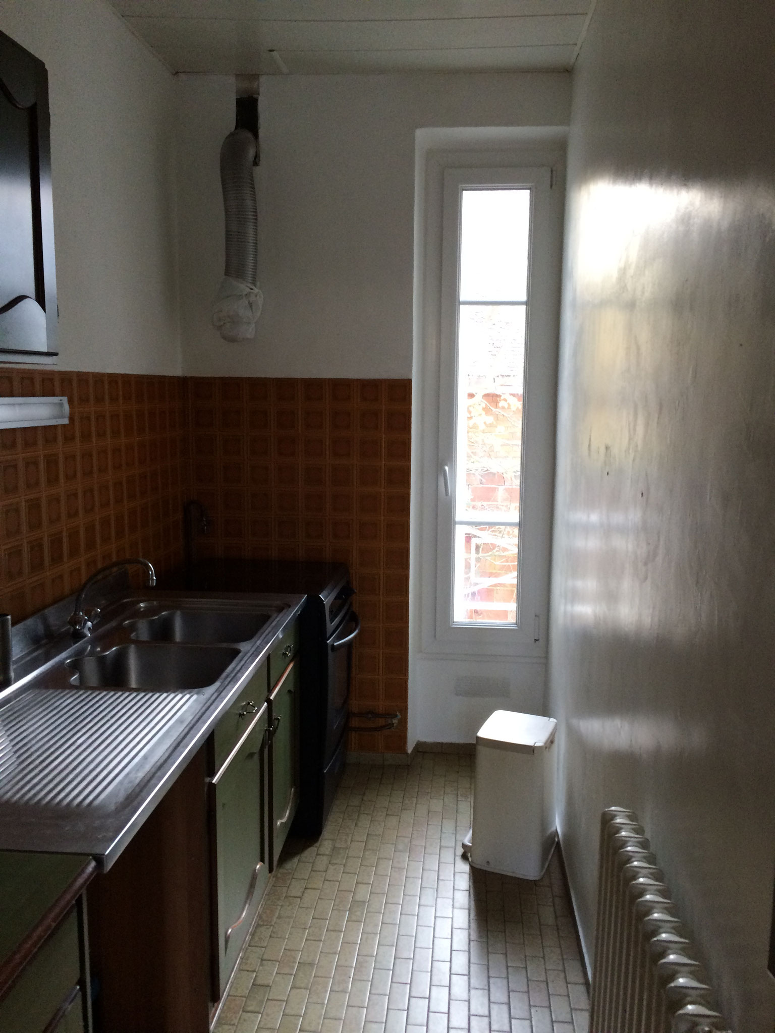 Cuisine étroite avant travaux, éclairée par une fenêtre à un seul vantail donnant sur le jardin.